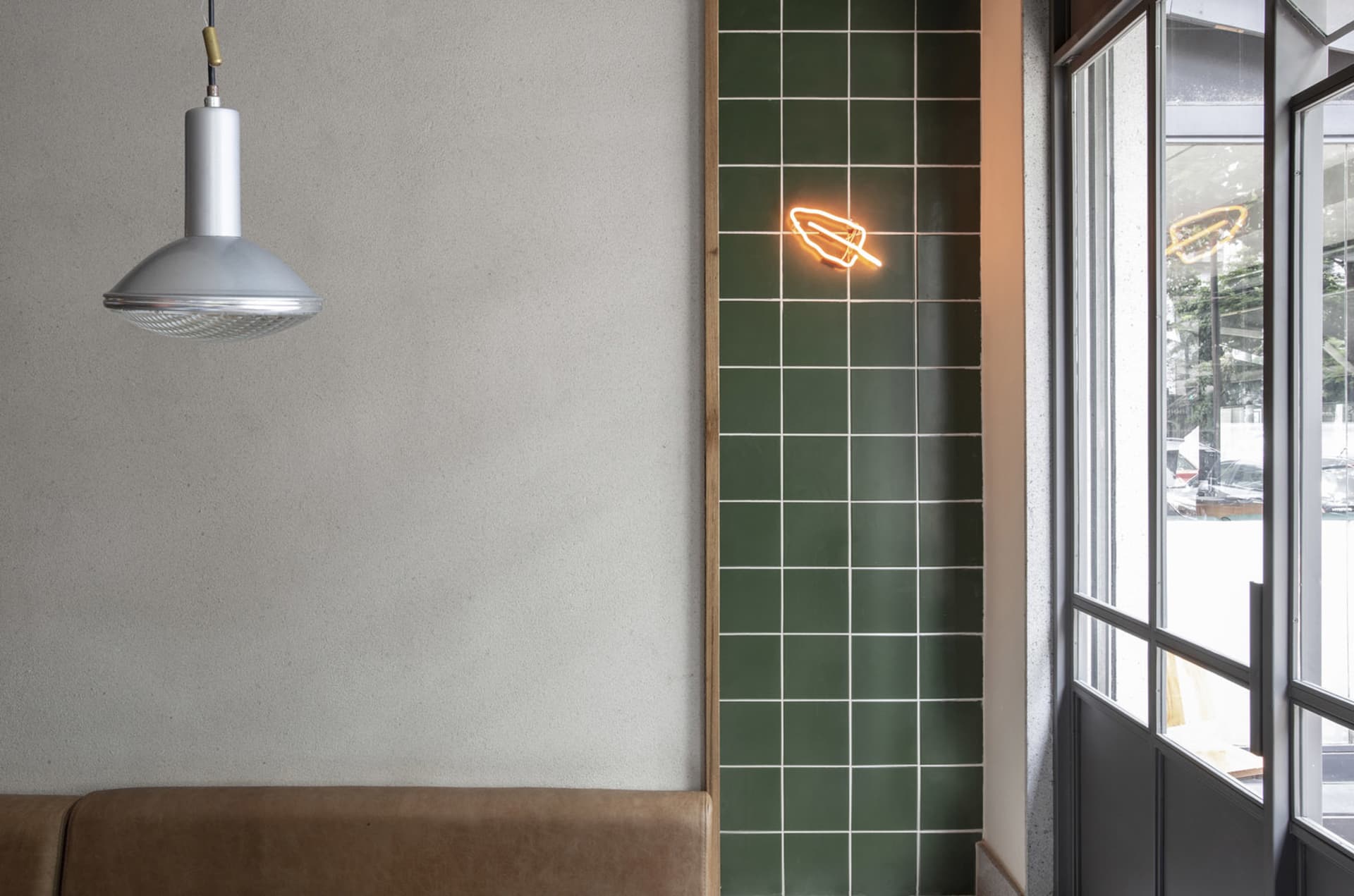 Cozy interior space with a green wall, neon sign, and two benches in a dimly lit room