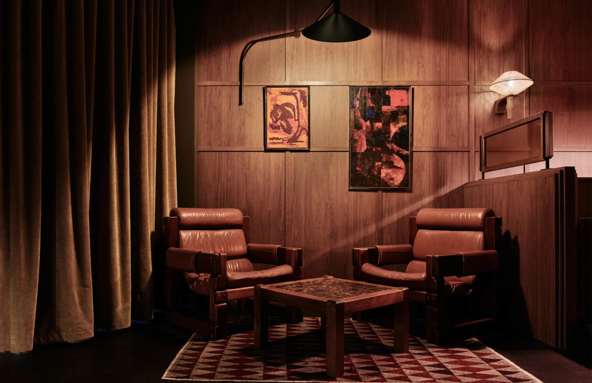 Cozy modern living space with leather chairs, a wooden table, and a couch, well-lit with natural or artificial light