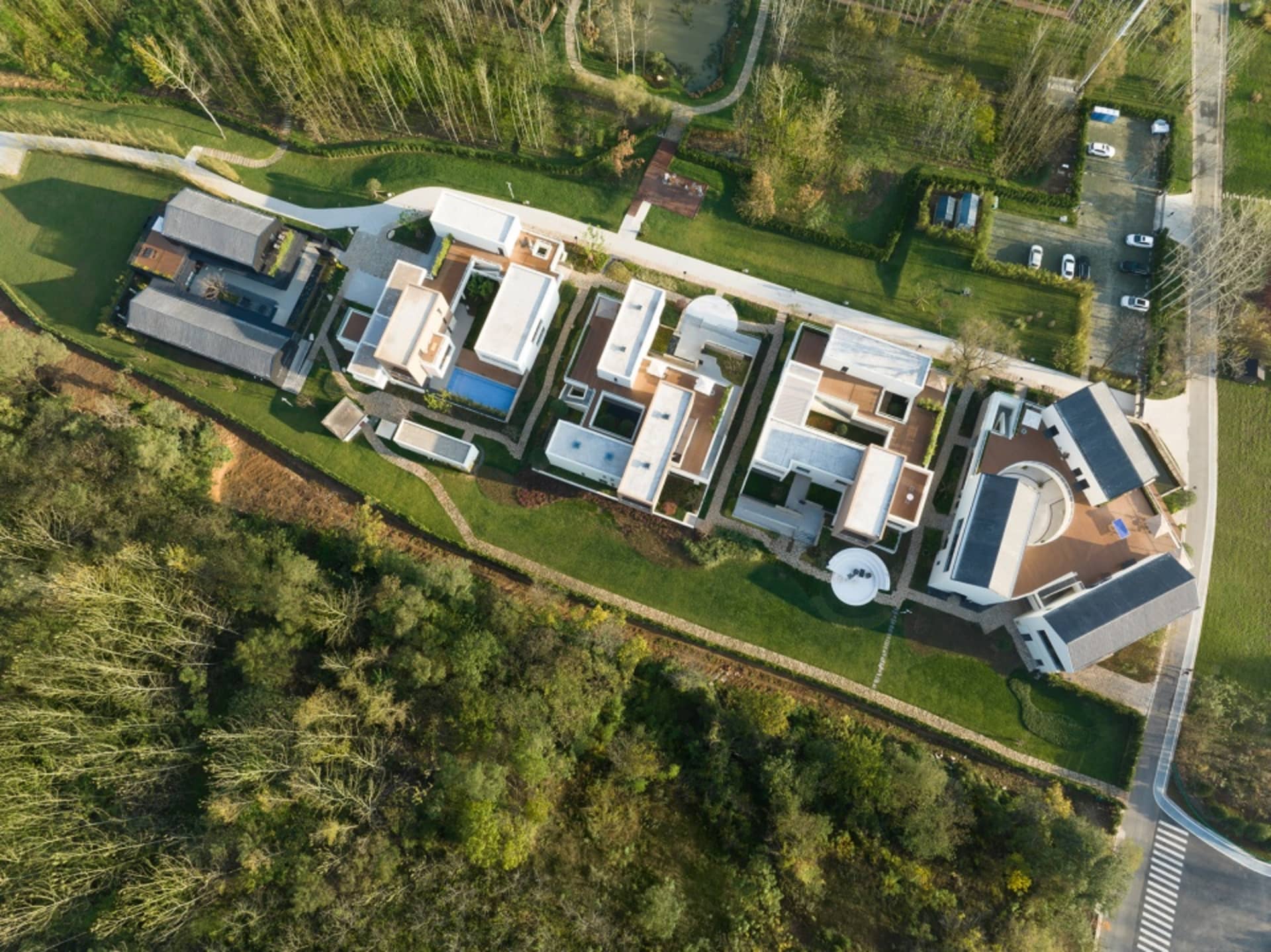 Aerial view of a modern house with multiple stories, featuring a mix of concrete, glass, and wood materials, and ample natural light from numerous windows