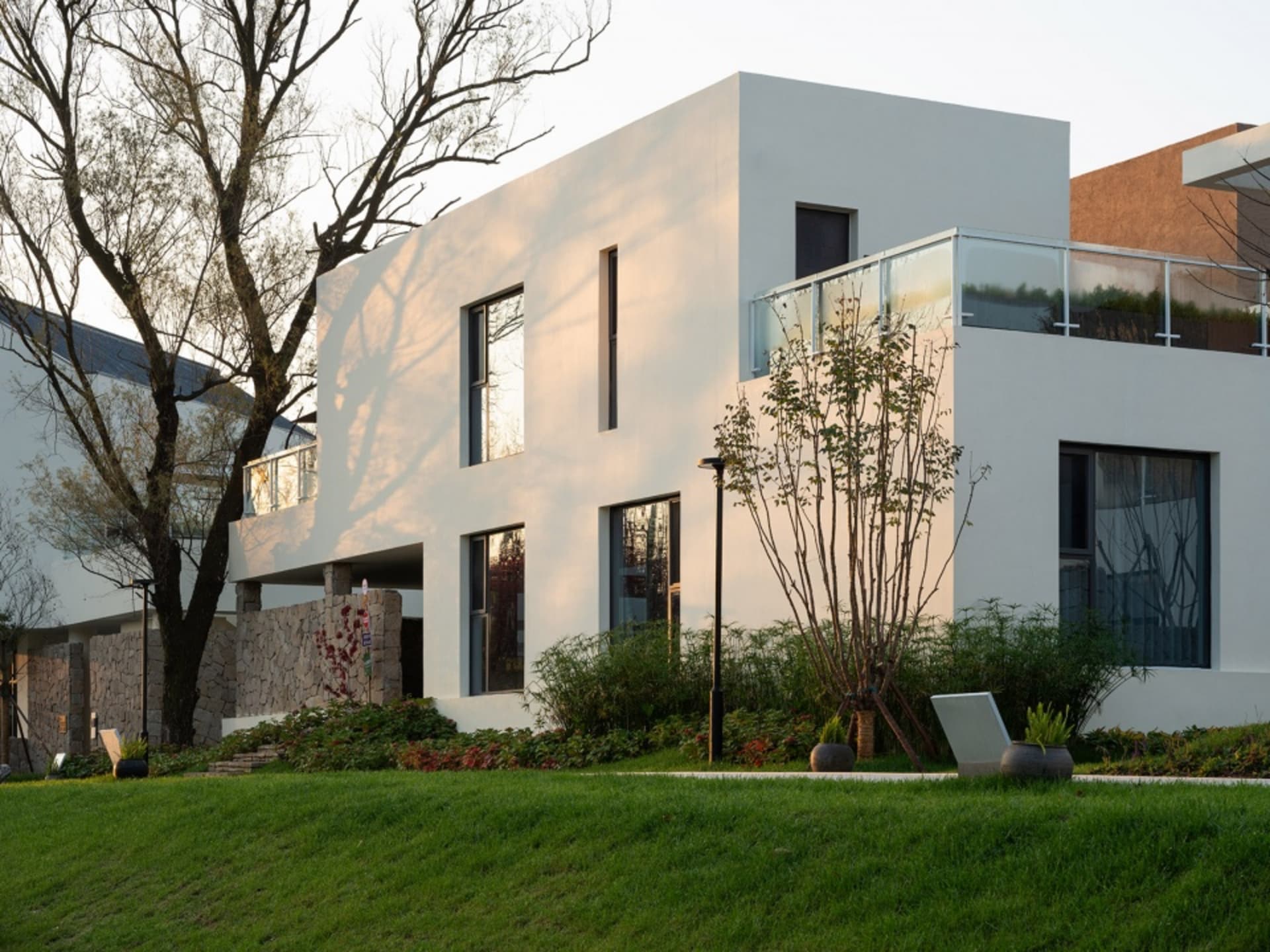 A modern house with a white facade, brown accents, and multiple windows, surrounded by trees, creating a comfortable and inviting atmosphere