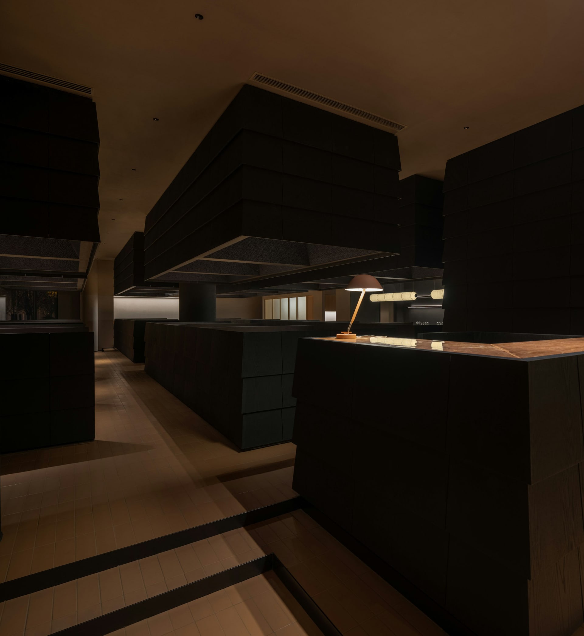 Dark kitchen with wooden floors, black cabinets, and two overhead lights