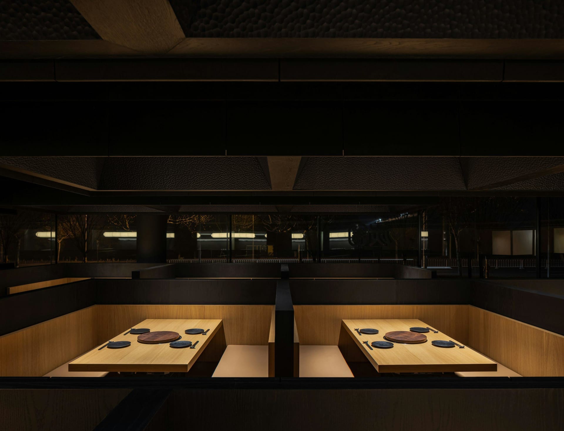 燈光昏暗的餐廳，設有兩張餐桌和椅子，營造舒適氛圍