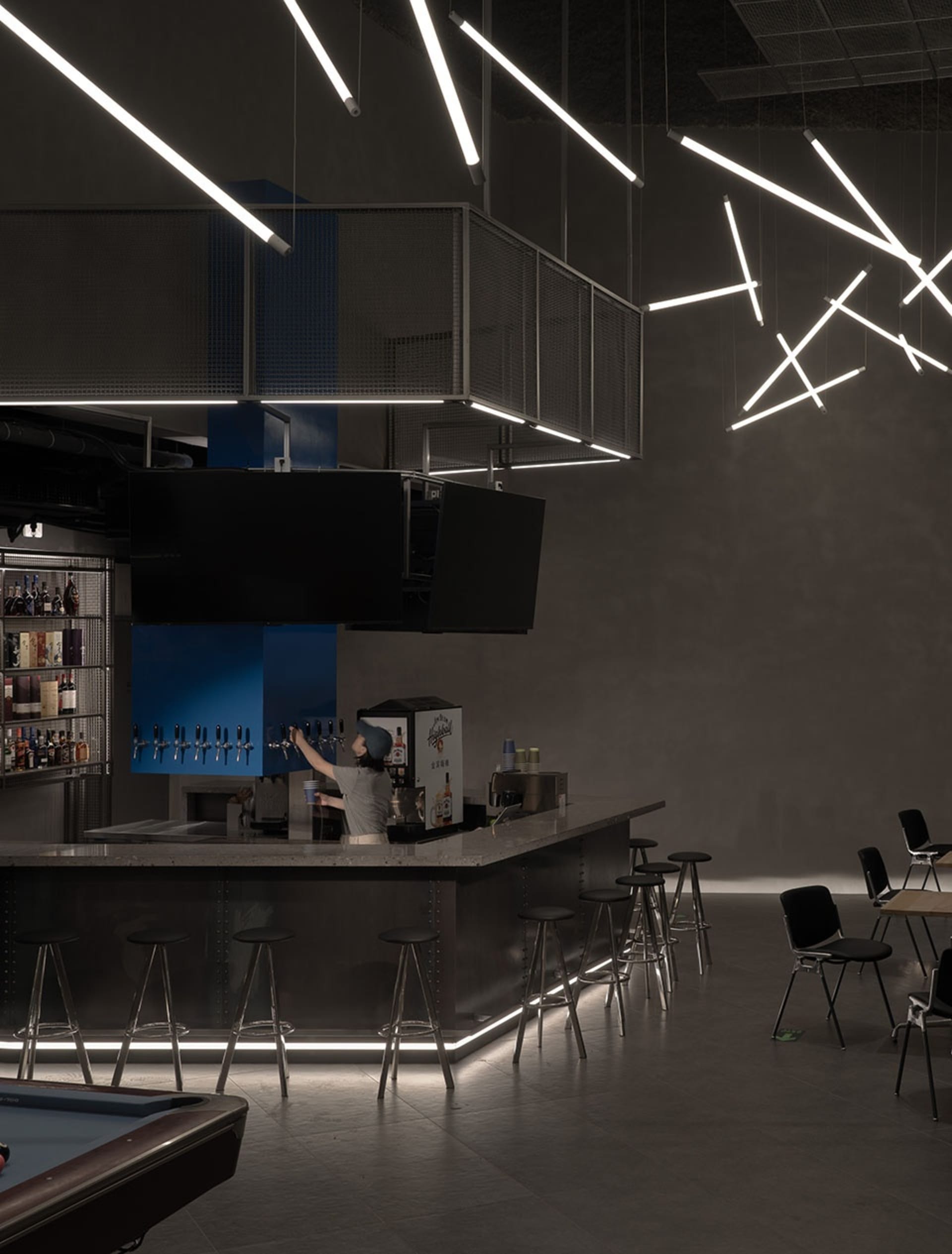 A casual bar area with a long wooden counter, stools, bottles, cups, and a bowl, creating a welcoming atmosphere for socializing