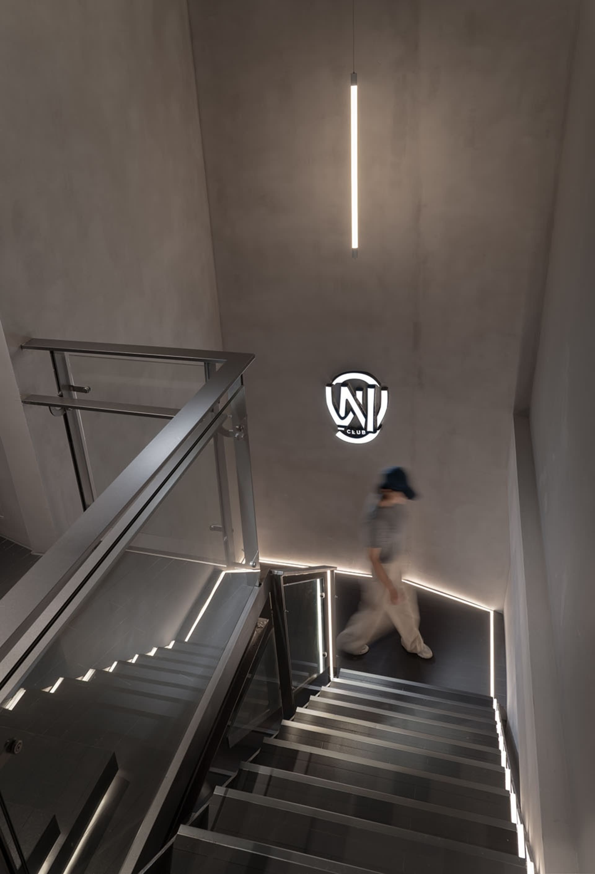 A man walks down a modern metal staircase with a glass railing in a building with a sense of movement and activity