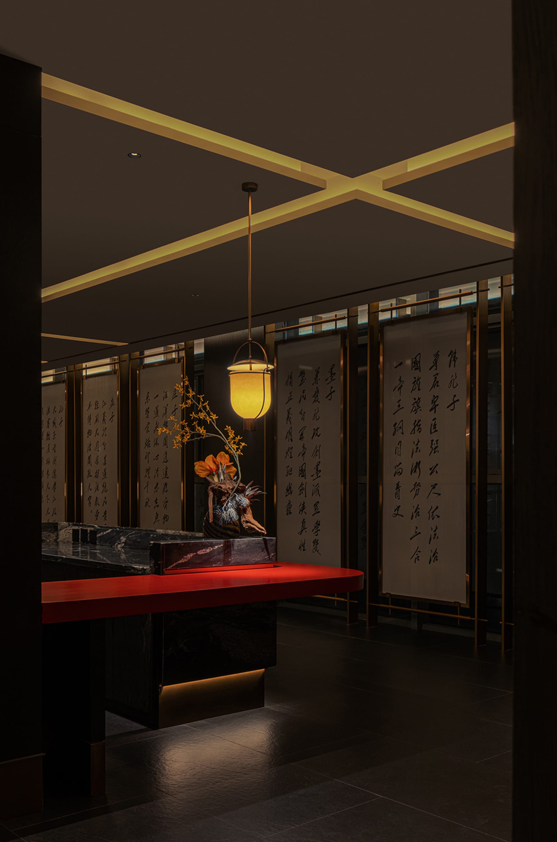 燈光昏暗的亞洲餐廳內部，紅色檯面、黃色燈具，以及牆上的東方文字
