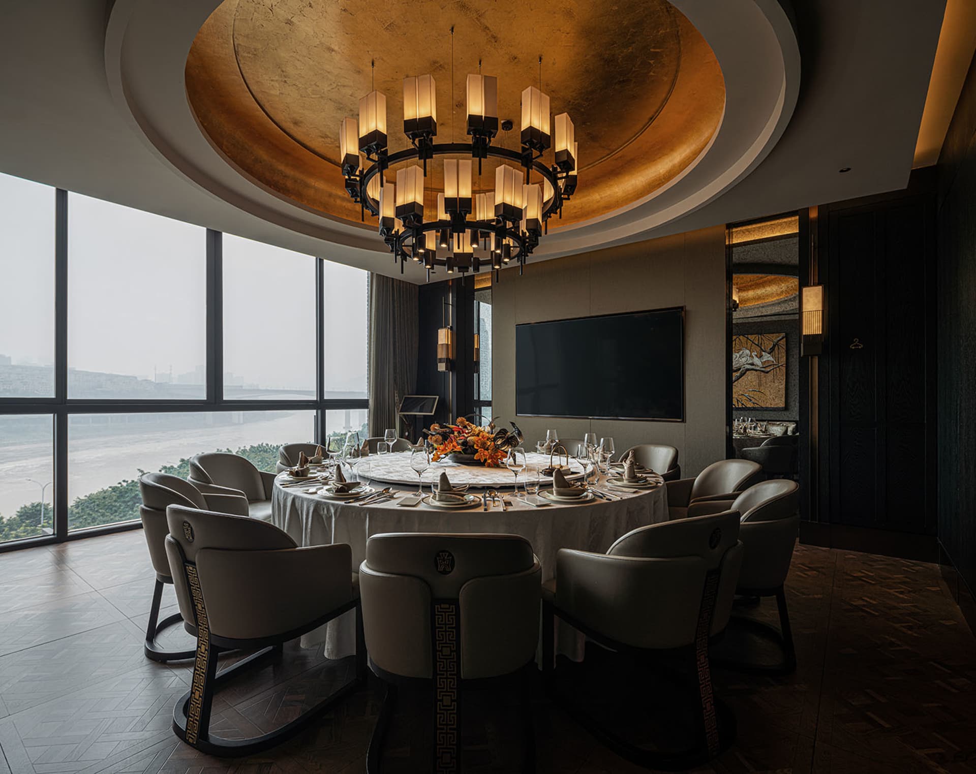 A dining area with a round table set with various items, surrounded by chairs, in a room with a gold ceiling and sophisticated ambiance