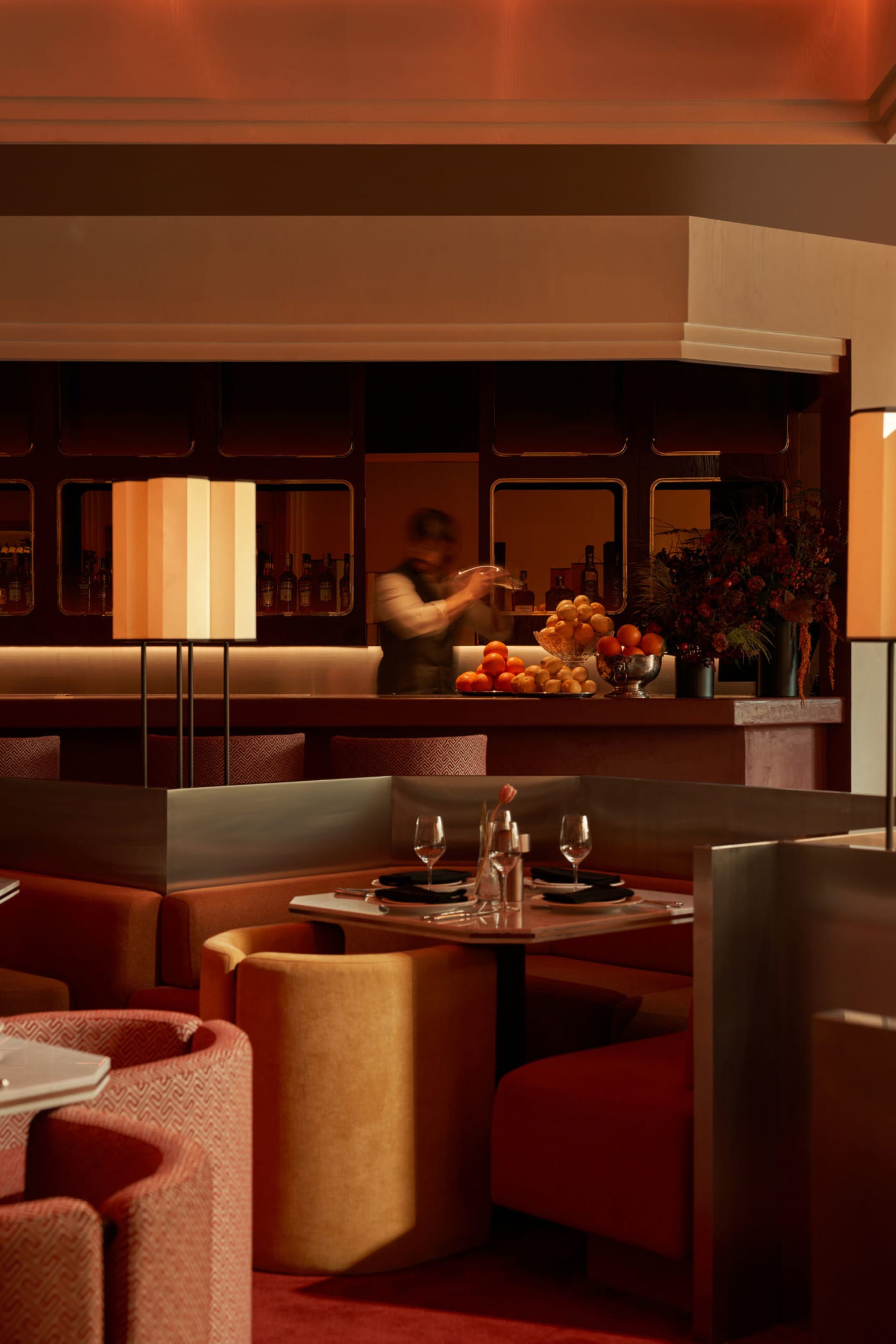 Sophisticated restaurant interior with a bar, dining tables, and wine glasses, set for dinner service