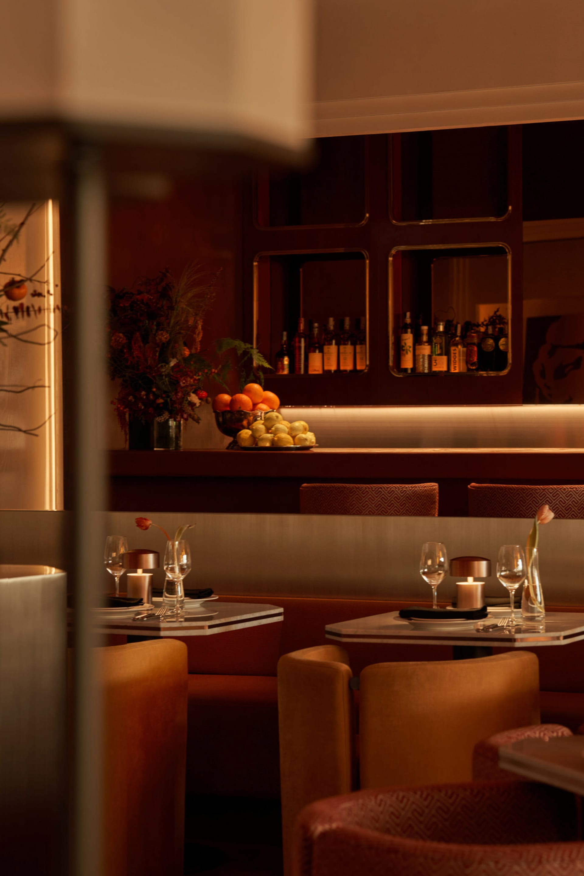 Sophisticated restaurant interior with a bar, wine glasses, and a cozy dining area with a couch and bottles on display