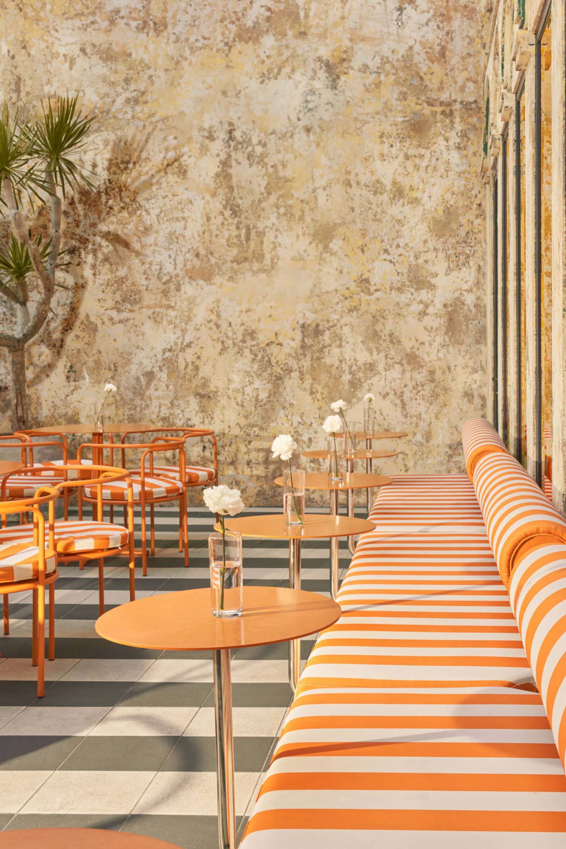 A relaxed outdoor patio with wicker chairs and tables, vases, and a warm atmosphere