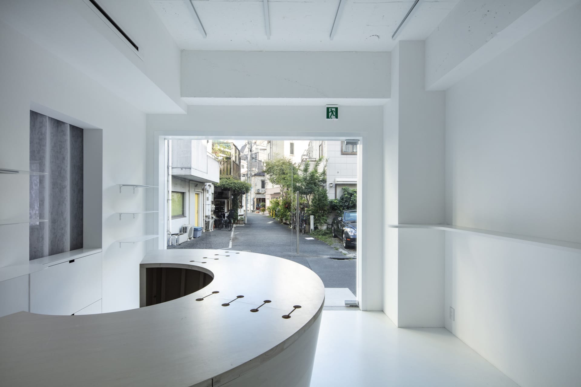 A bright and inviting open-plan room with a large window, dining table, and bicycle, featuring a mix of functionality and simplicity
