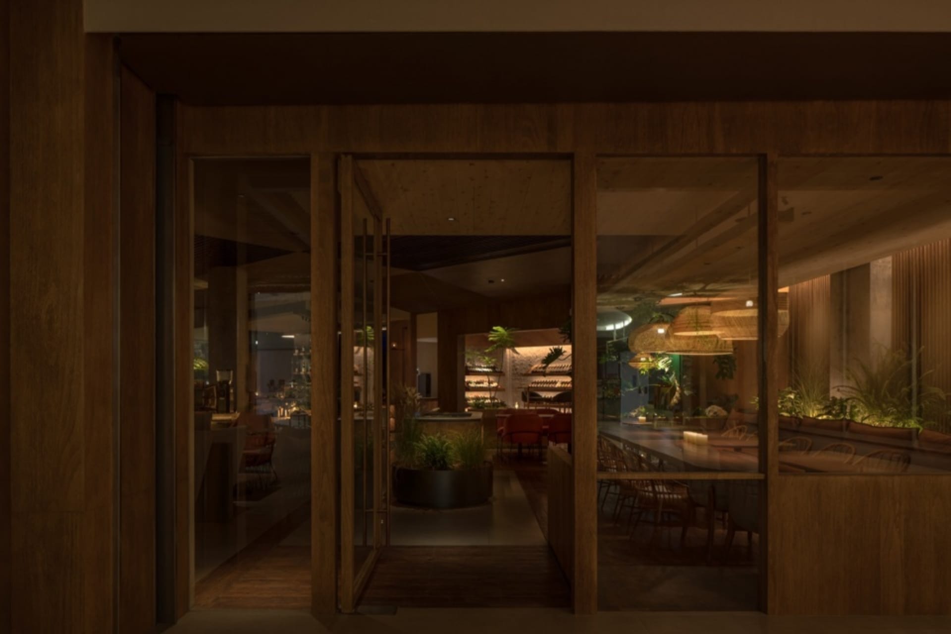 Open living area with wooden floors and walls, featuring a dining table, chairs, and a potted plant, creating a warm and inviting atmosphere
