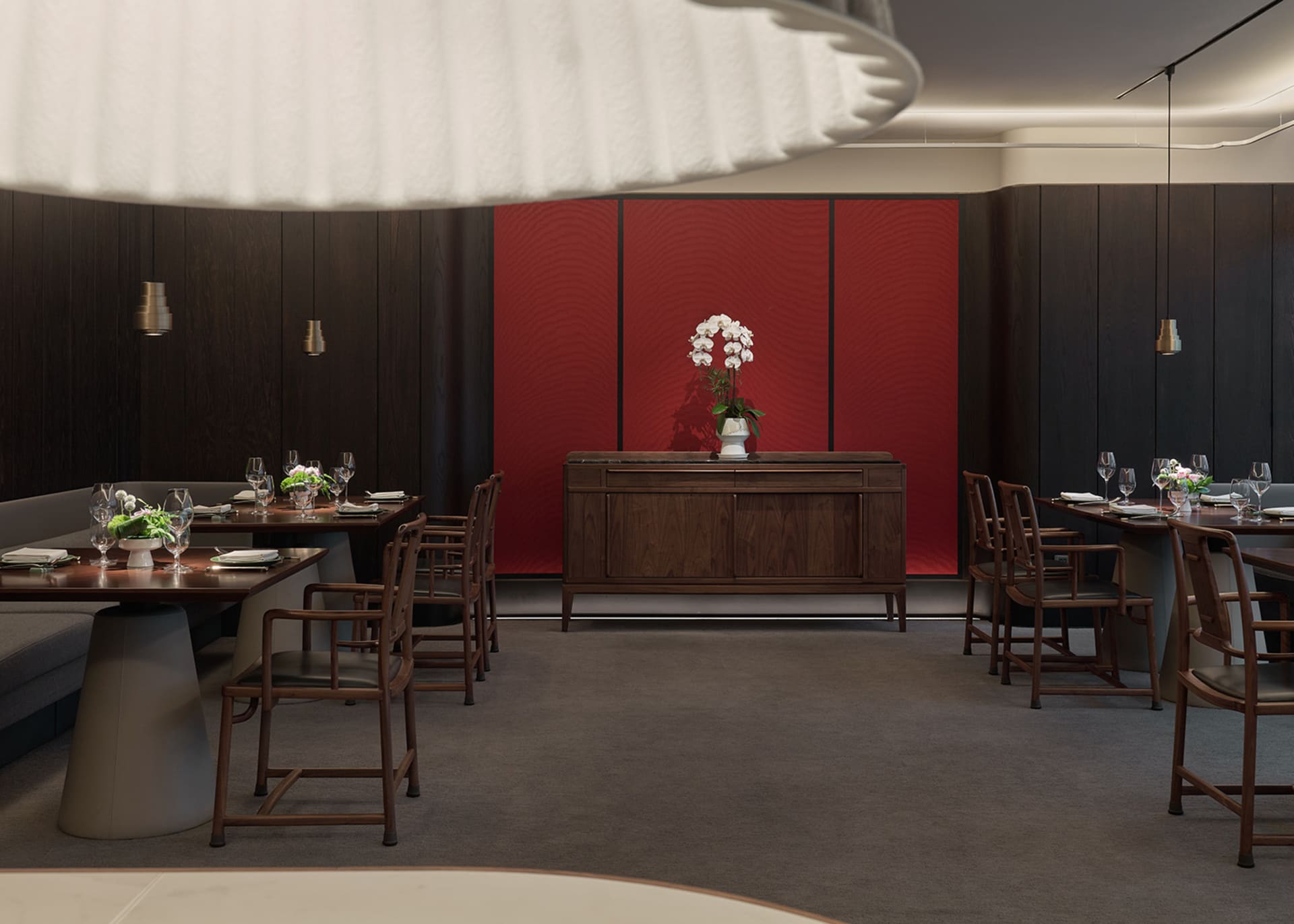Warm and inviting dining area with red walls, wooden furniture, and decorative vases with flowers