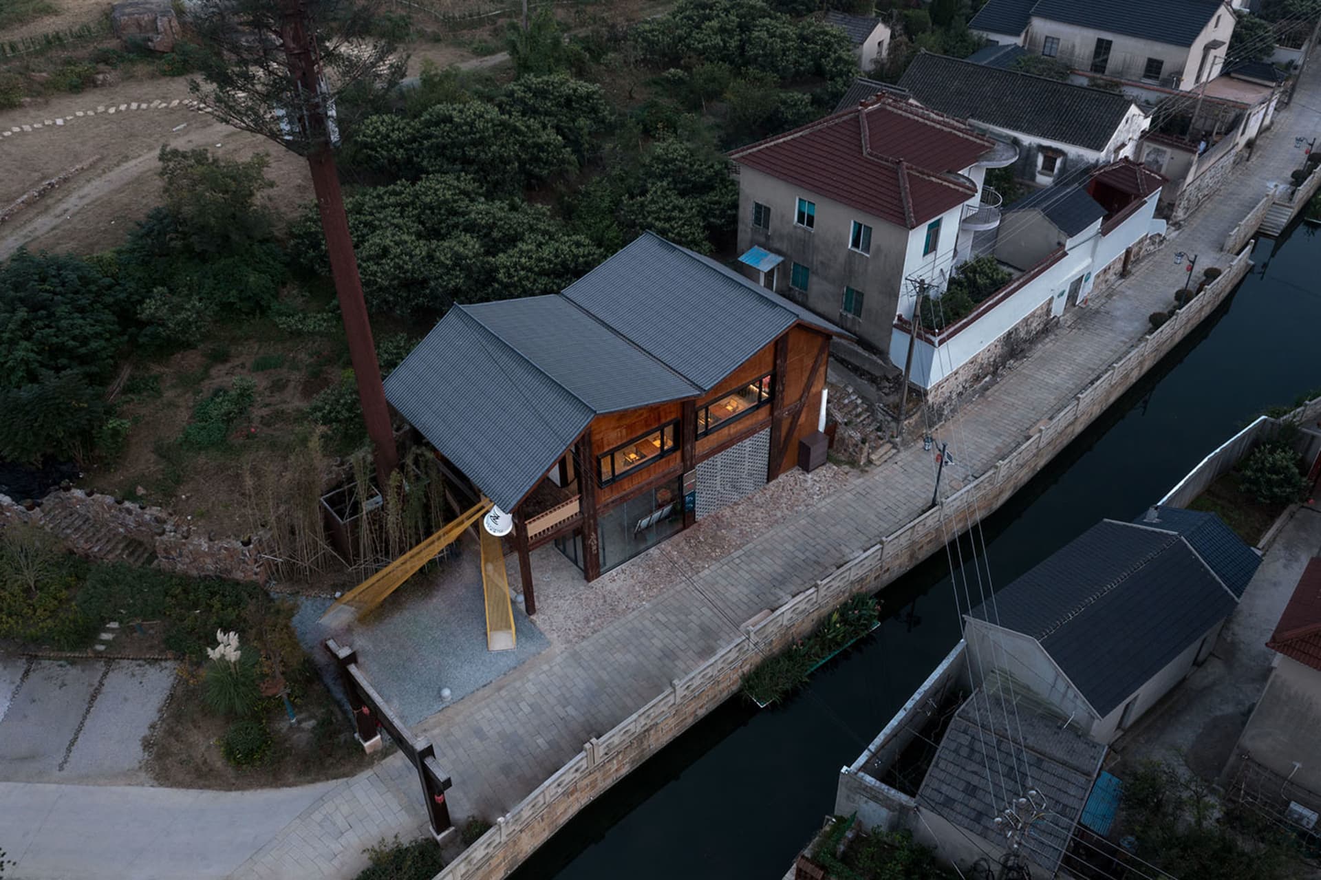 A house on stilts surrounded by trees, with a wooden structure and several windows providing natural light, set in a peaceful and serene environment