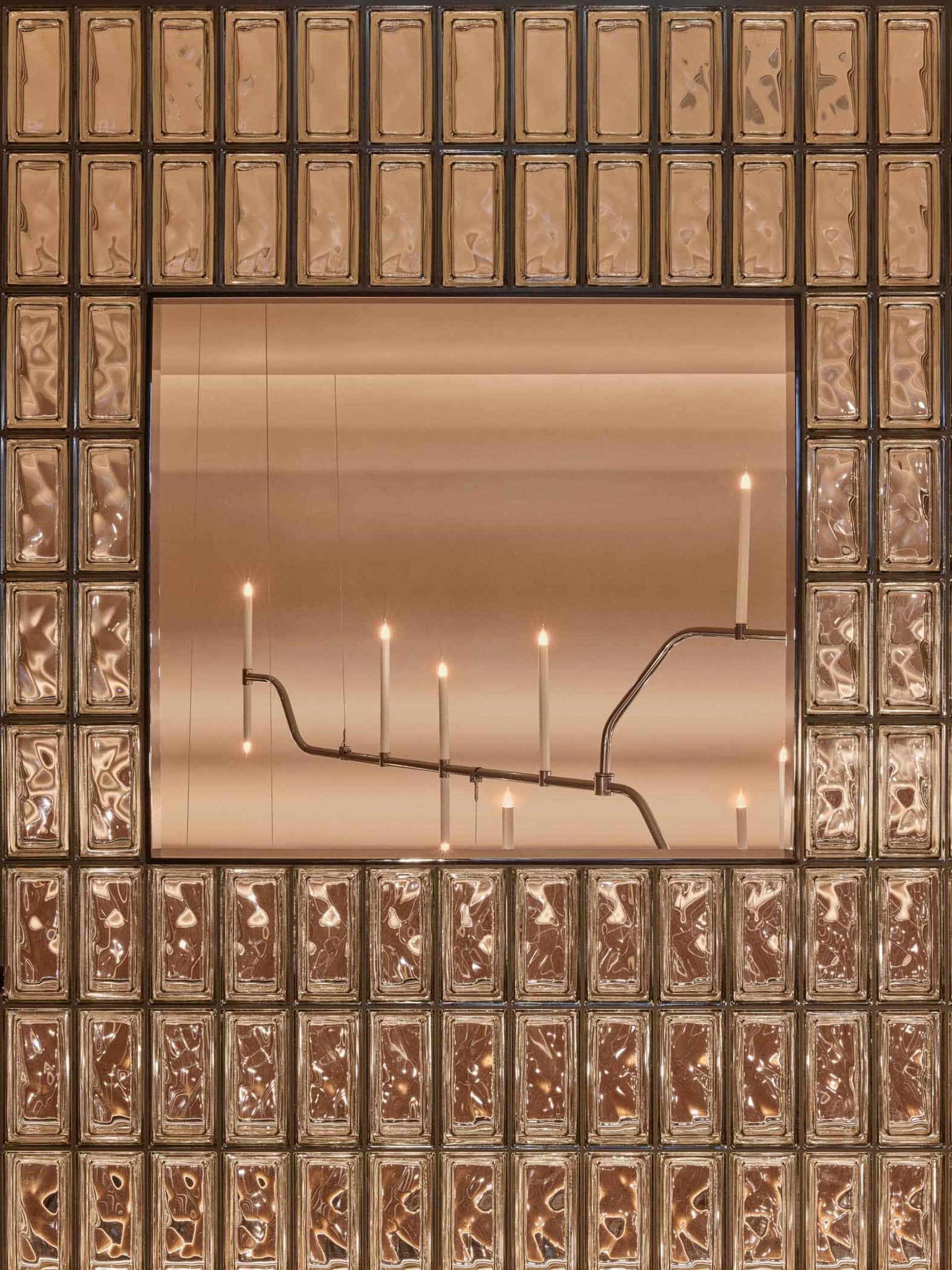 A sophisticated dining space with a large mirror, gold frame, and multiple lit candles creating a warm and inviting atmosphere