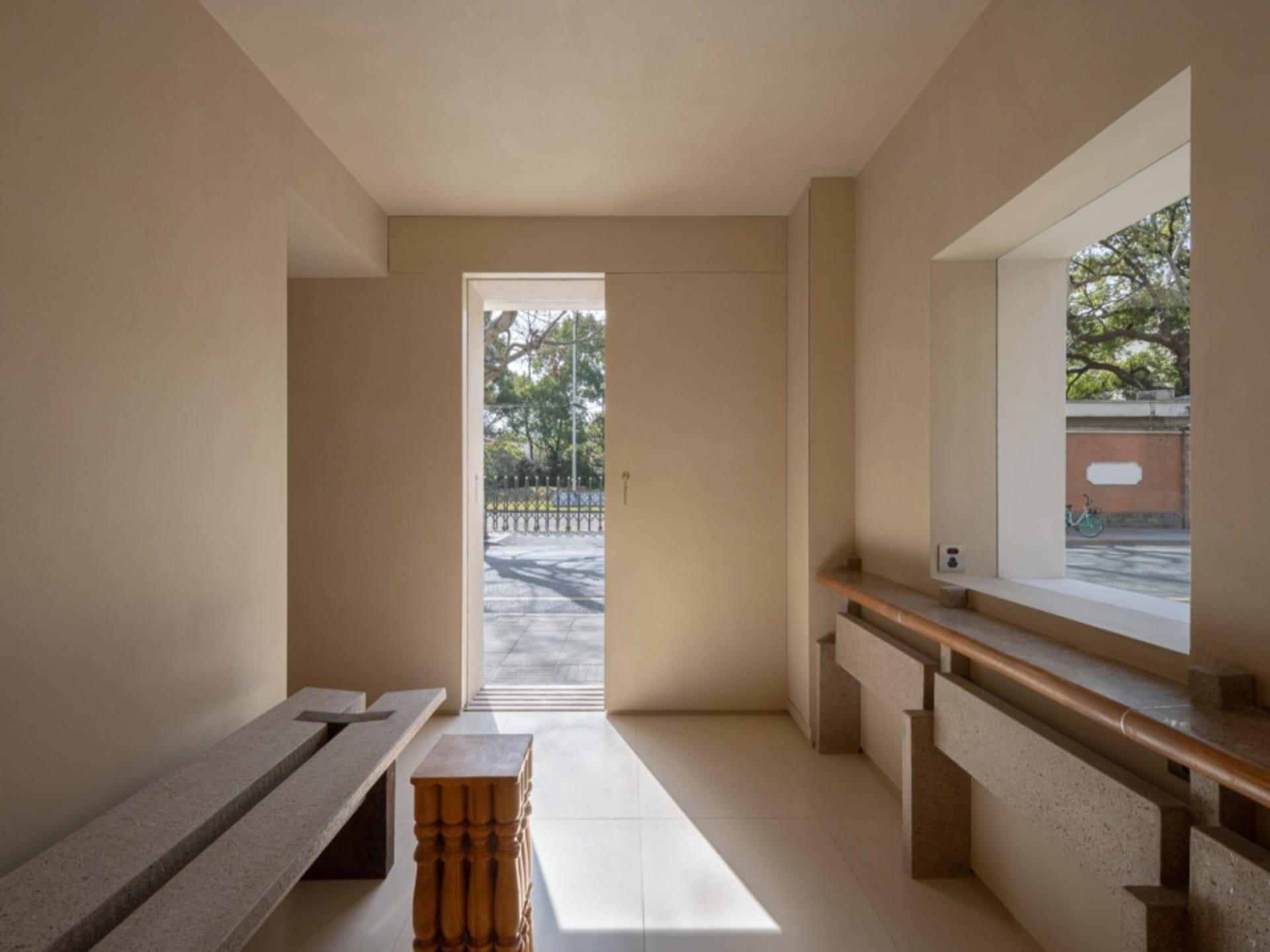 Empty open-plan living area with white walls, a doorway to another room, and benches in both spaces