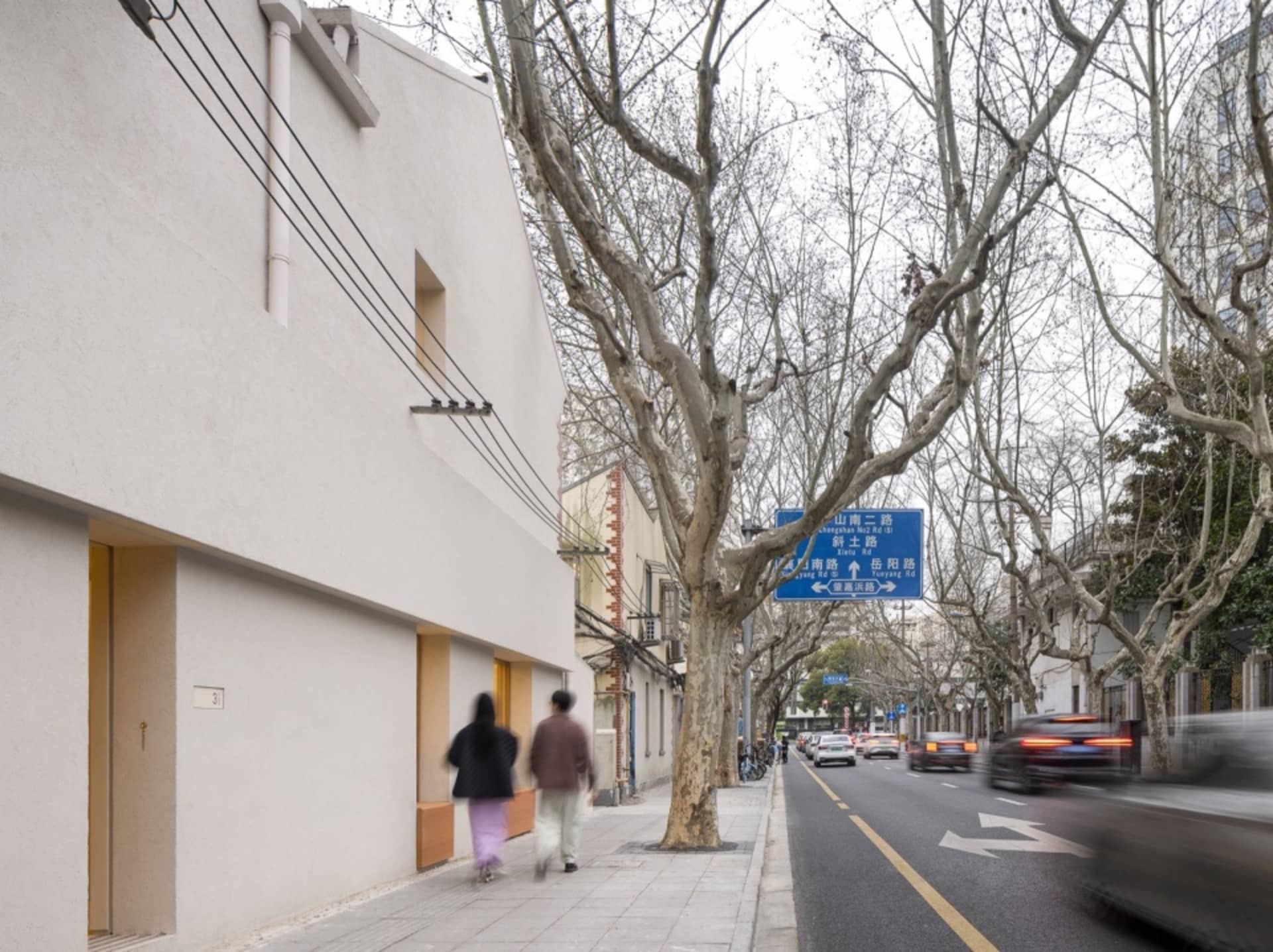 A busy city street scene with pedestrians and vehicles, surrounded by trees and urban elements