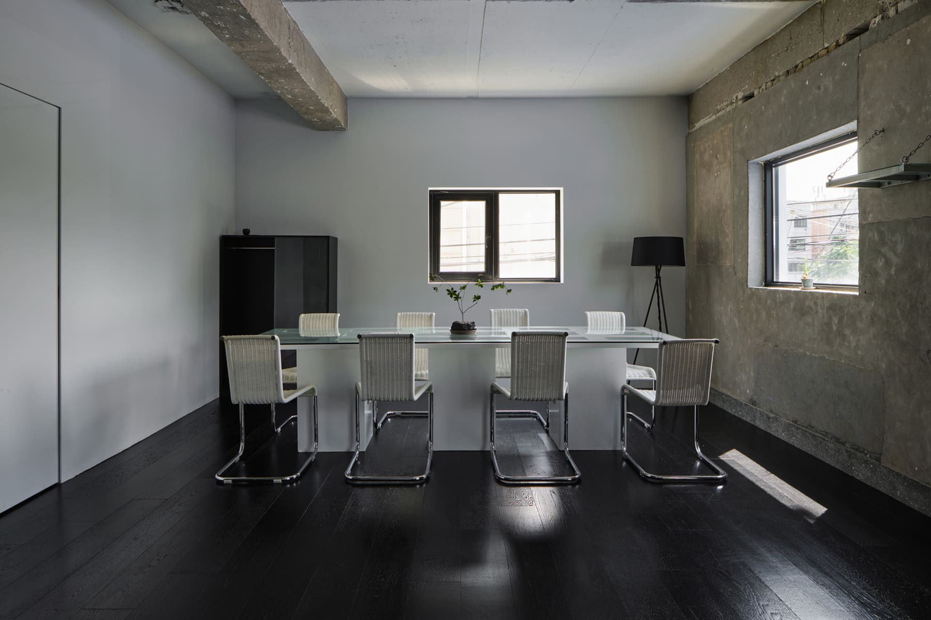 Empty modern dining room with a glass table surrounded by six chairs, black floor, and white walls