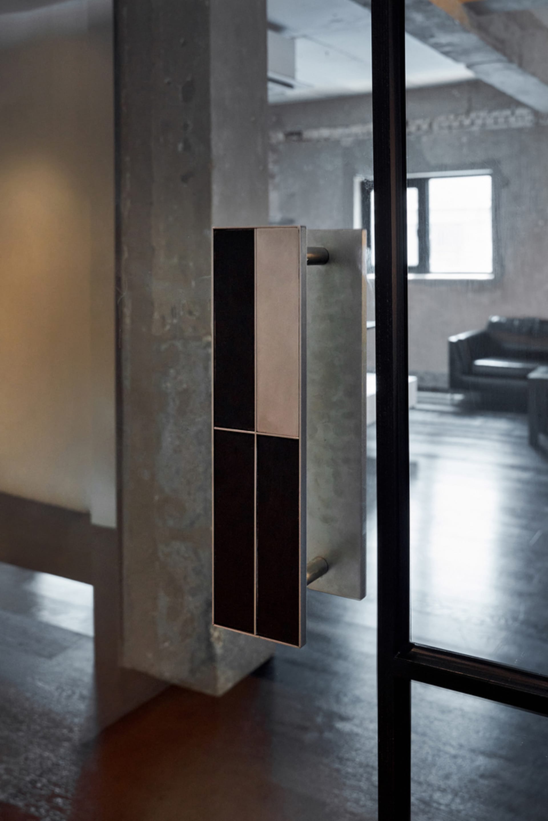 A minimalist entrance with a modern metal and glass door handle, set against a clean and well-lit background