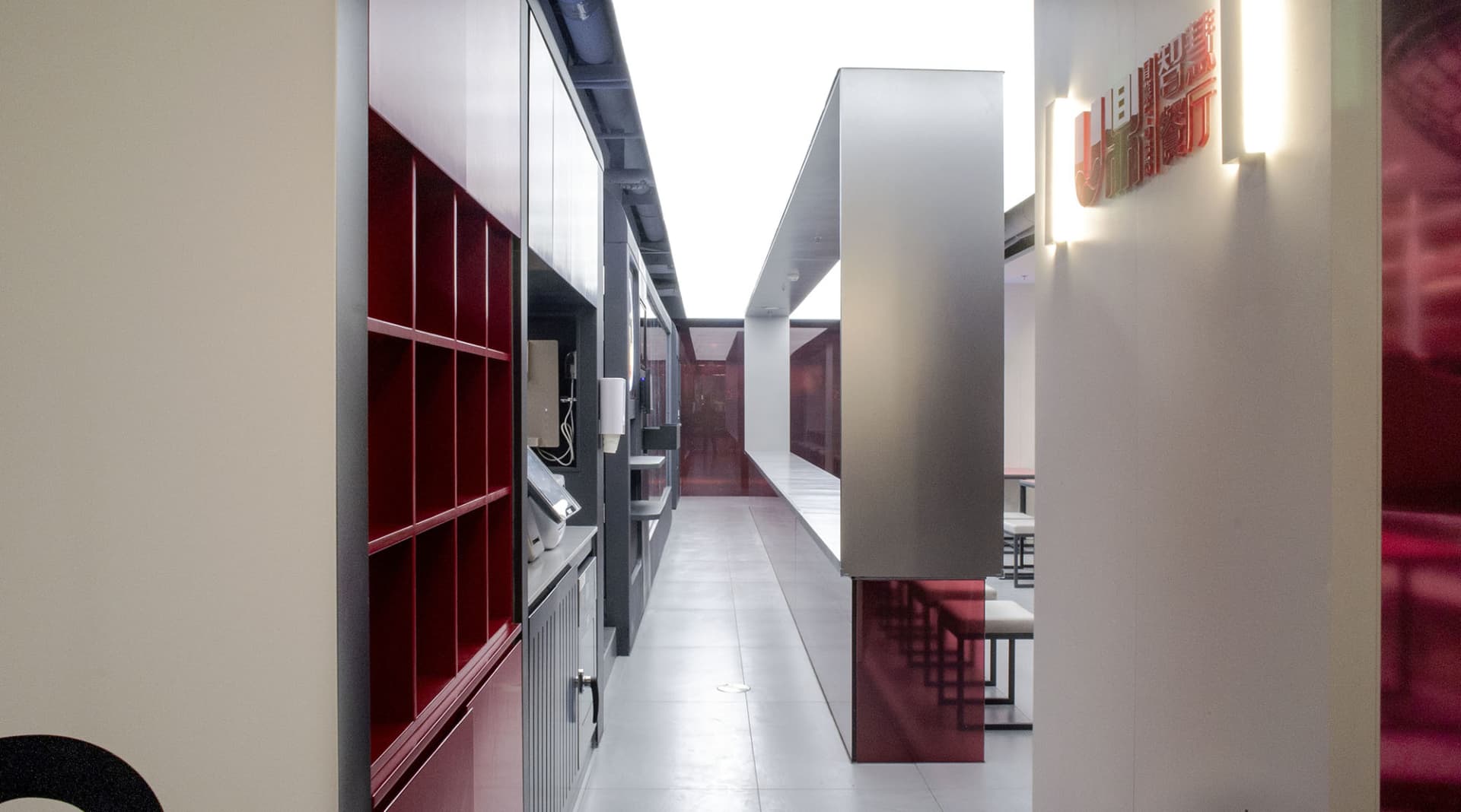 Industrial kitchen with red walls, grey floors, metal pillars, and a countertop with chairs, sink, and industrial feel