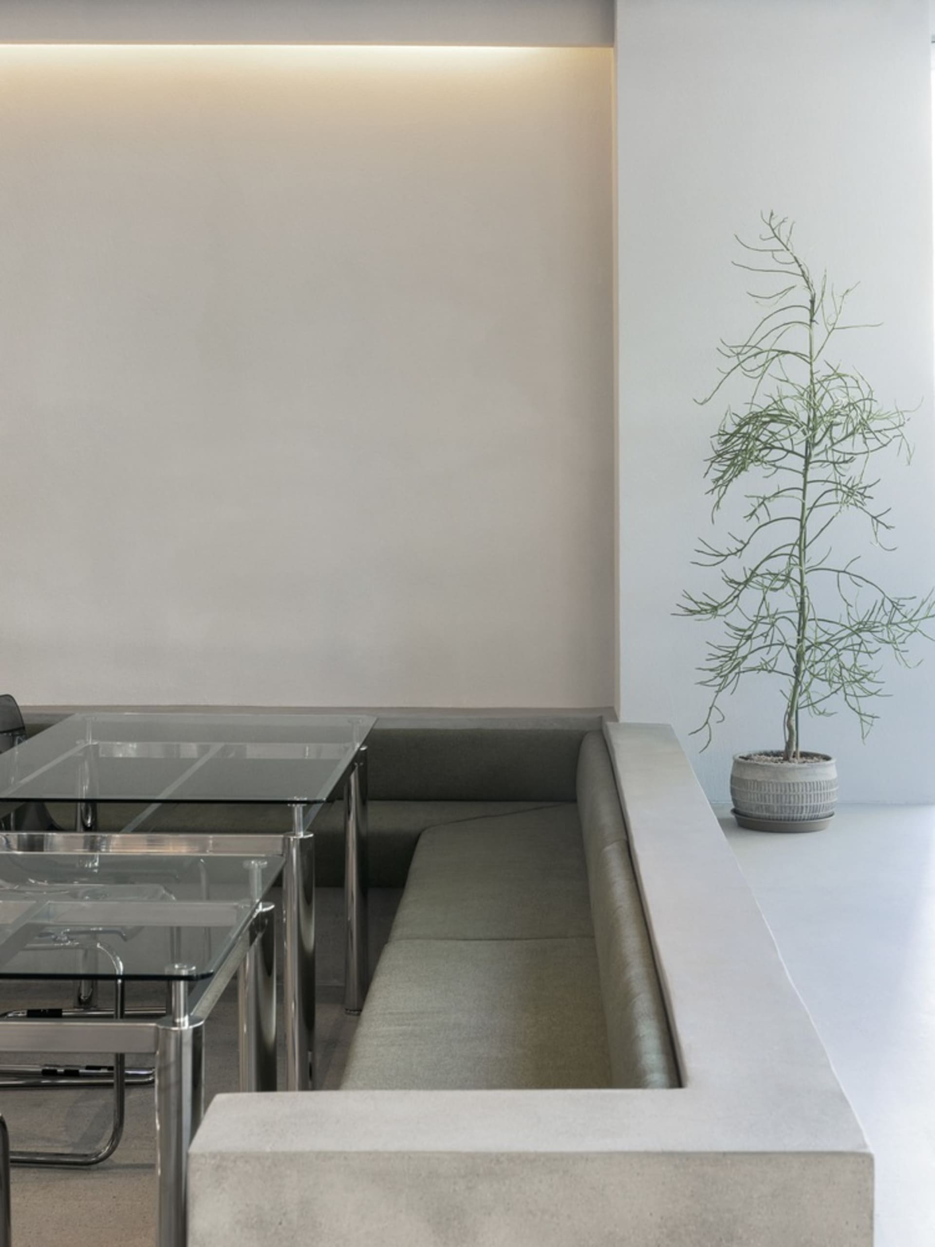 Empty room with a white wall and a green couch, two chairs, and a calm atmosphere
