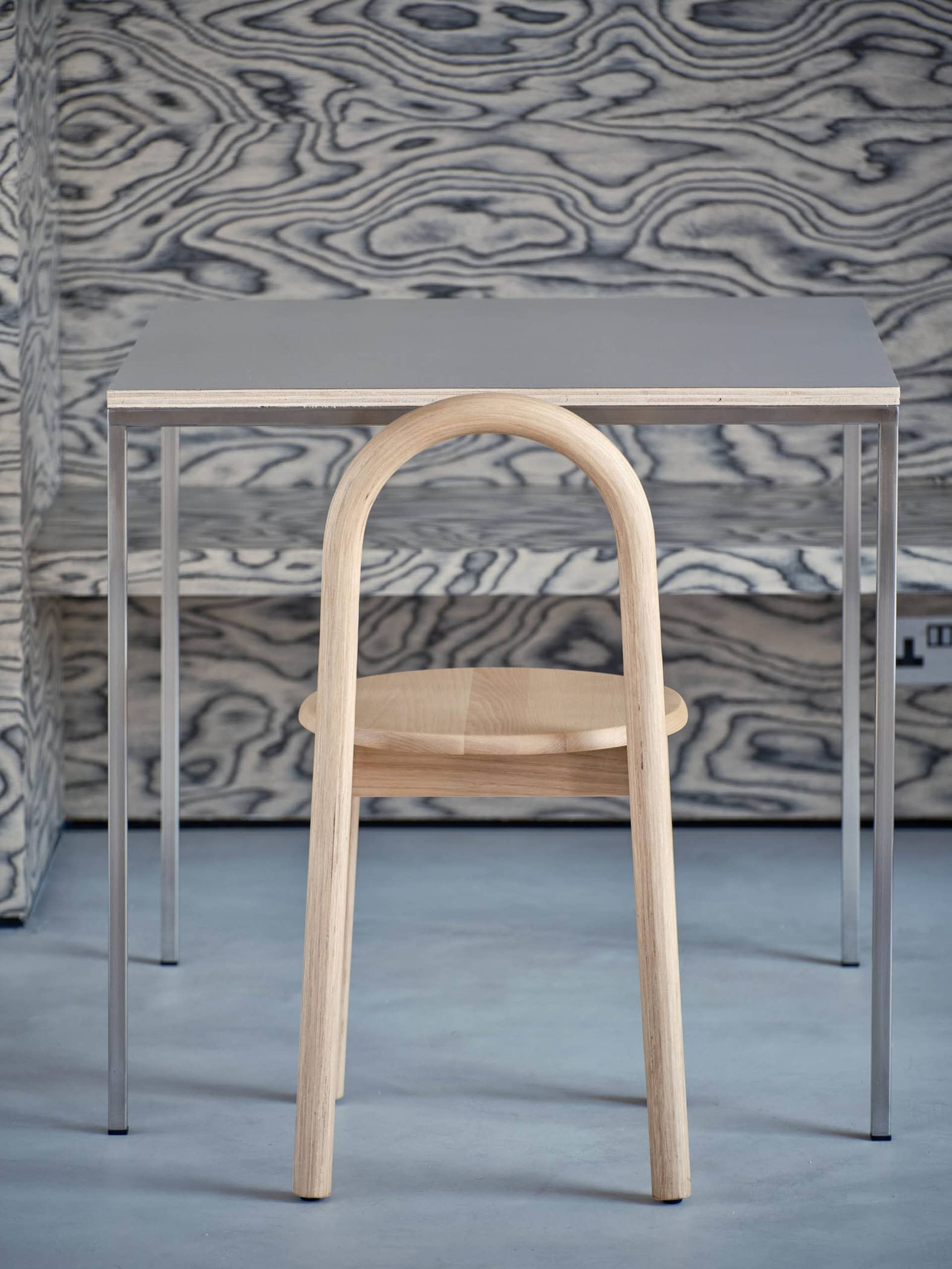 A professional office setting with a wooden chair in front of a metal desk, featuring a unique chair design and organized workspace