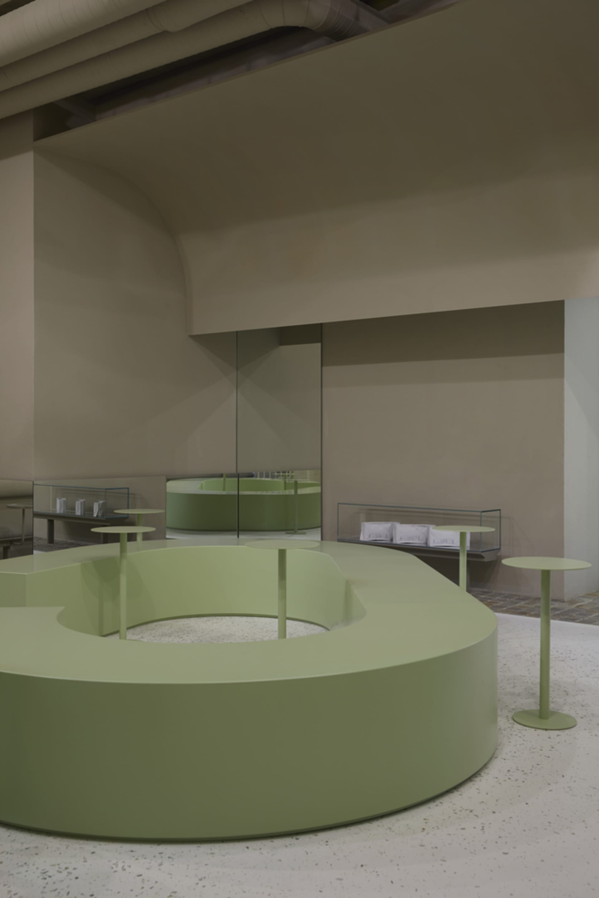 A modern interior design concept featuring green walls and floors, with tables and chairs in a spacious open area