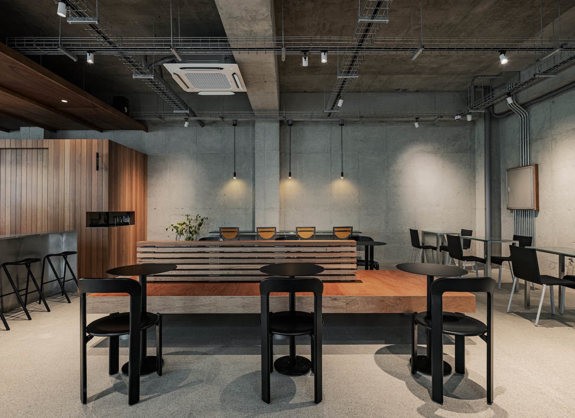 空蕩蕩的現代餐廳，擁有水泥牆面與地板，桌椅及碗盤，營造出乾淨且吸引人的用餐環境