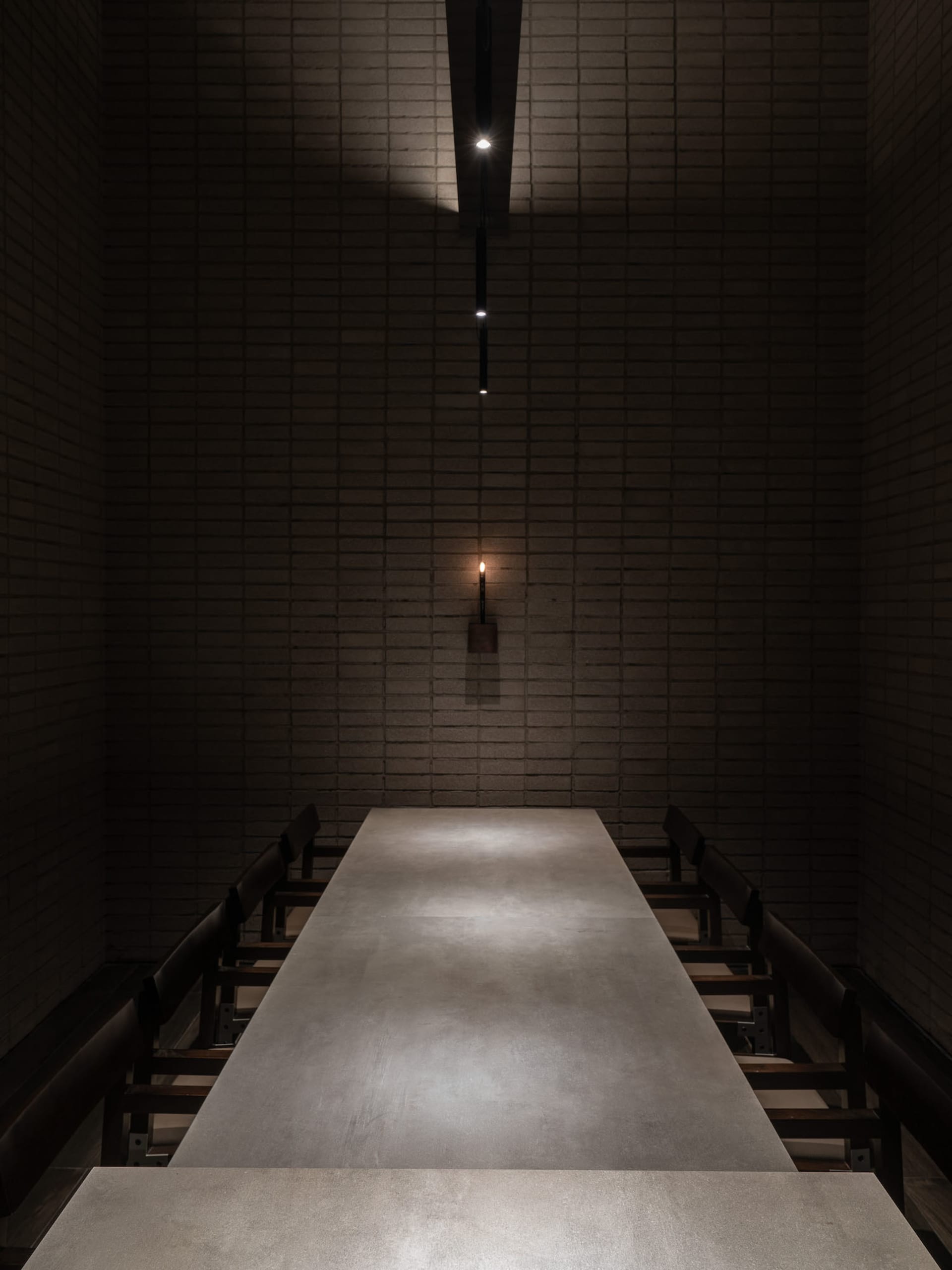 A formal dining area with a long table and chairs, surrounded by brick walls and suitable for hosting elegant gatherings