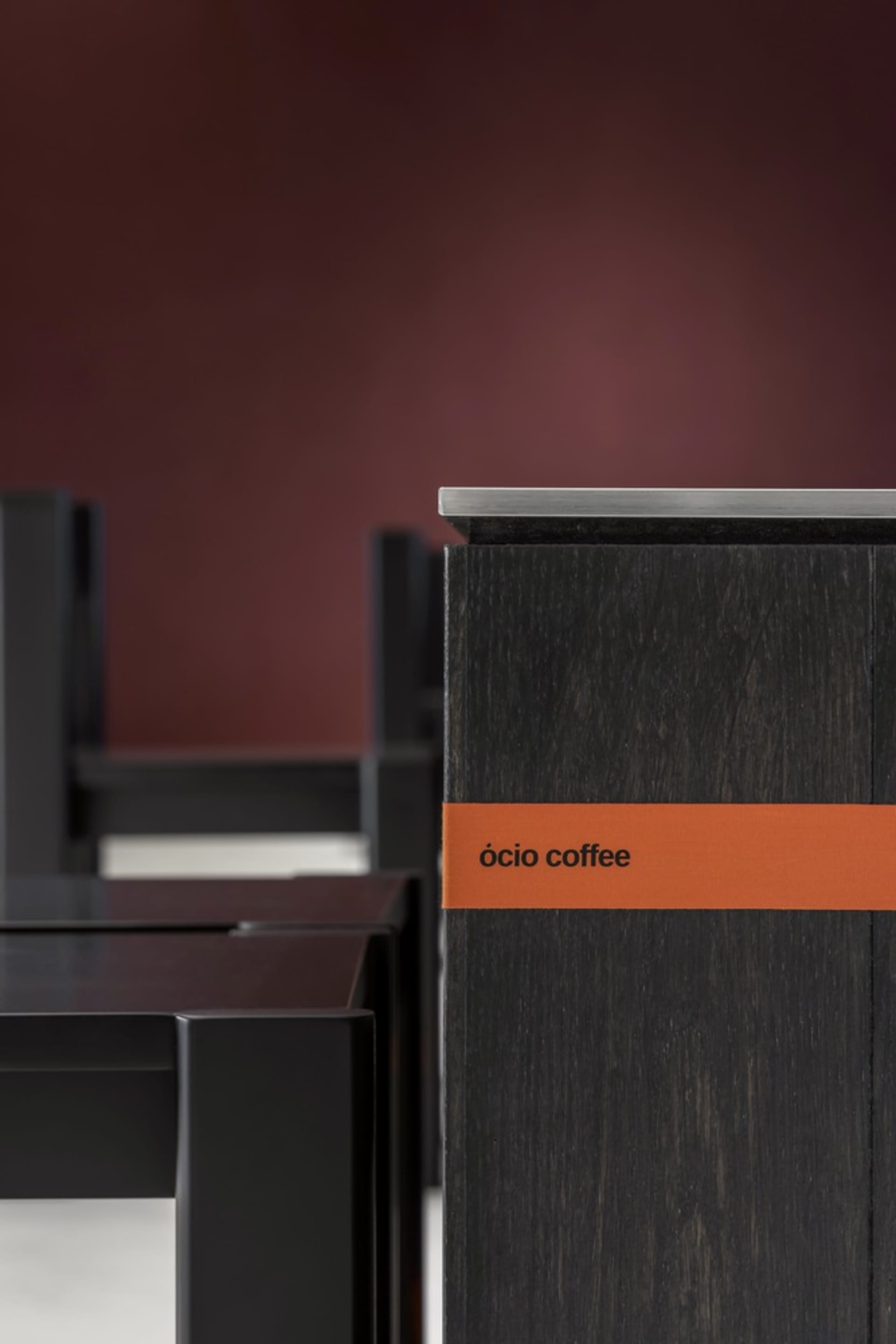 A black wooden coffee table with a red label on its side sits in front of a red background wall, showcasing its sleek design