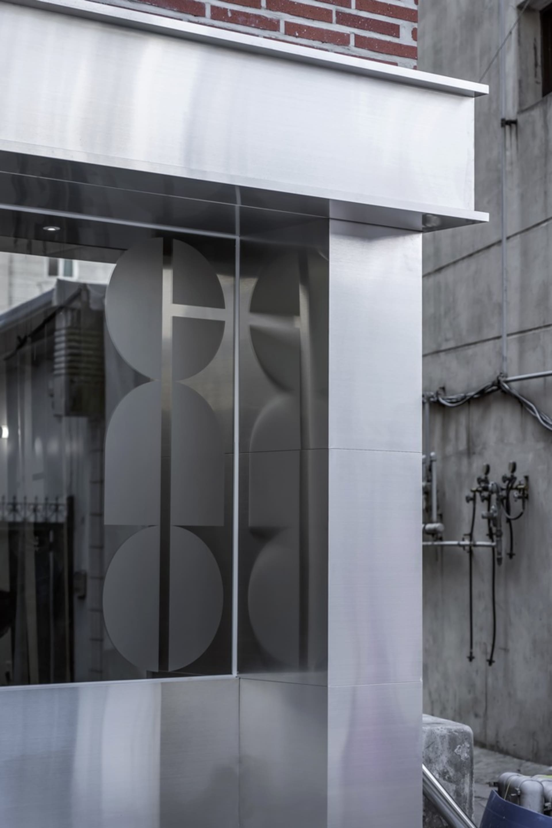 A modern building with a glass facade and three circular glass features, set against a neutral background