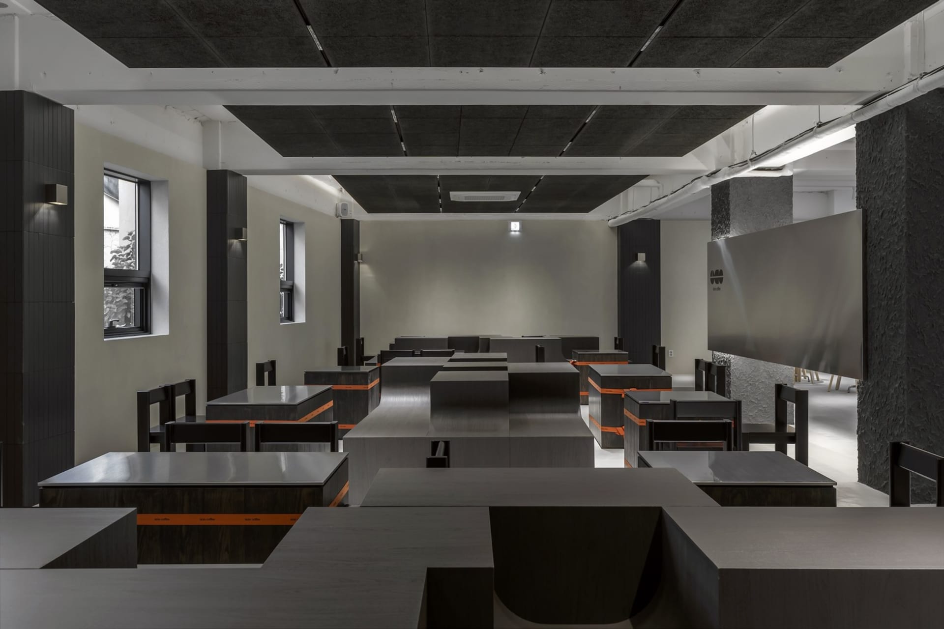 Empty classroom with long tables and chairs, well-lit and designed for group discussions or presentations