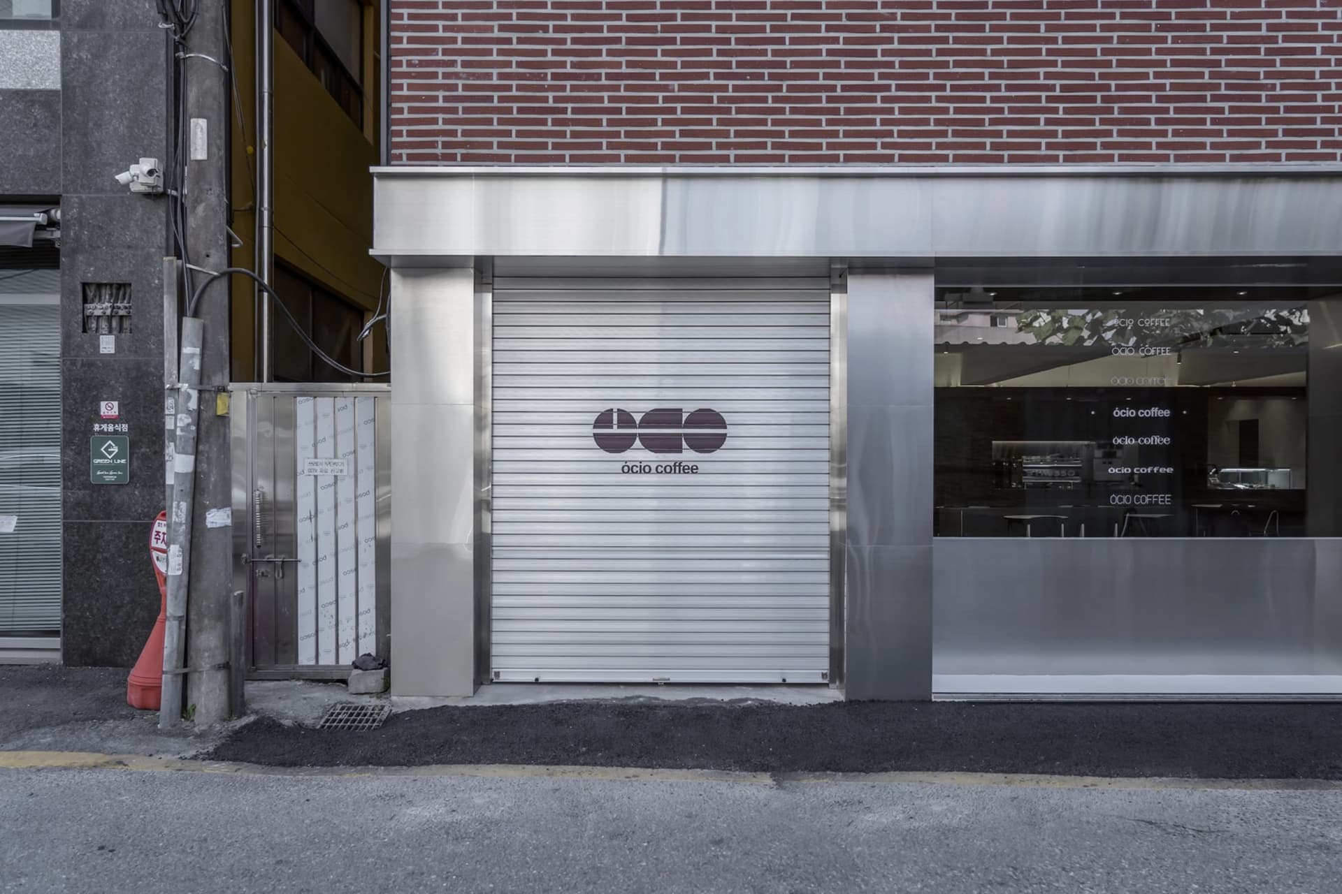 現代建築外觀，銀色立面搭配玻璃入口及兩側門戶，為咖啡廳營造溫馨吸引的氛圍
