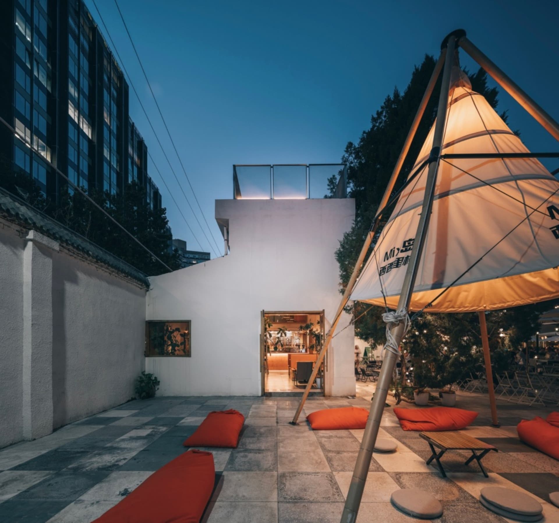 現代風格的戶外用餐區，設有大型遮陽傘、橙色坐墊與盆栽，位於餐廳露台