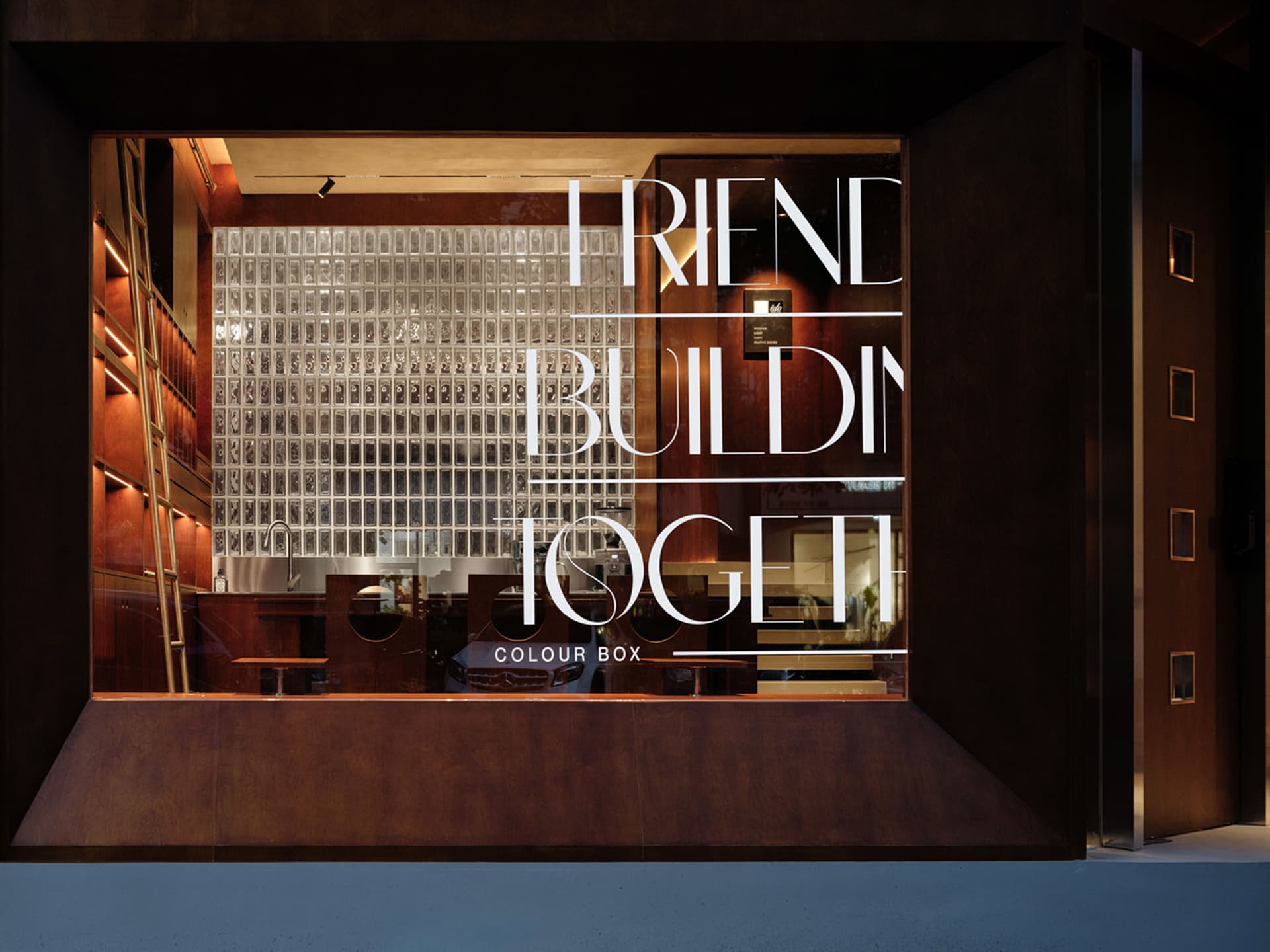A warm and welcoming restaurant interior with dining tables, a storefront display, and a sign reading Friend Building Together