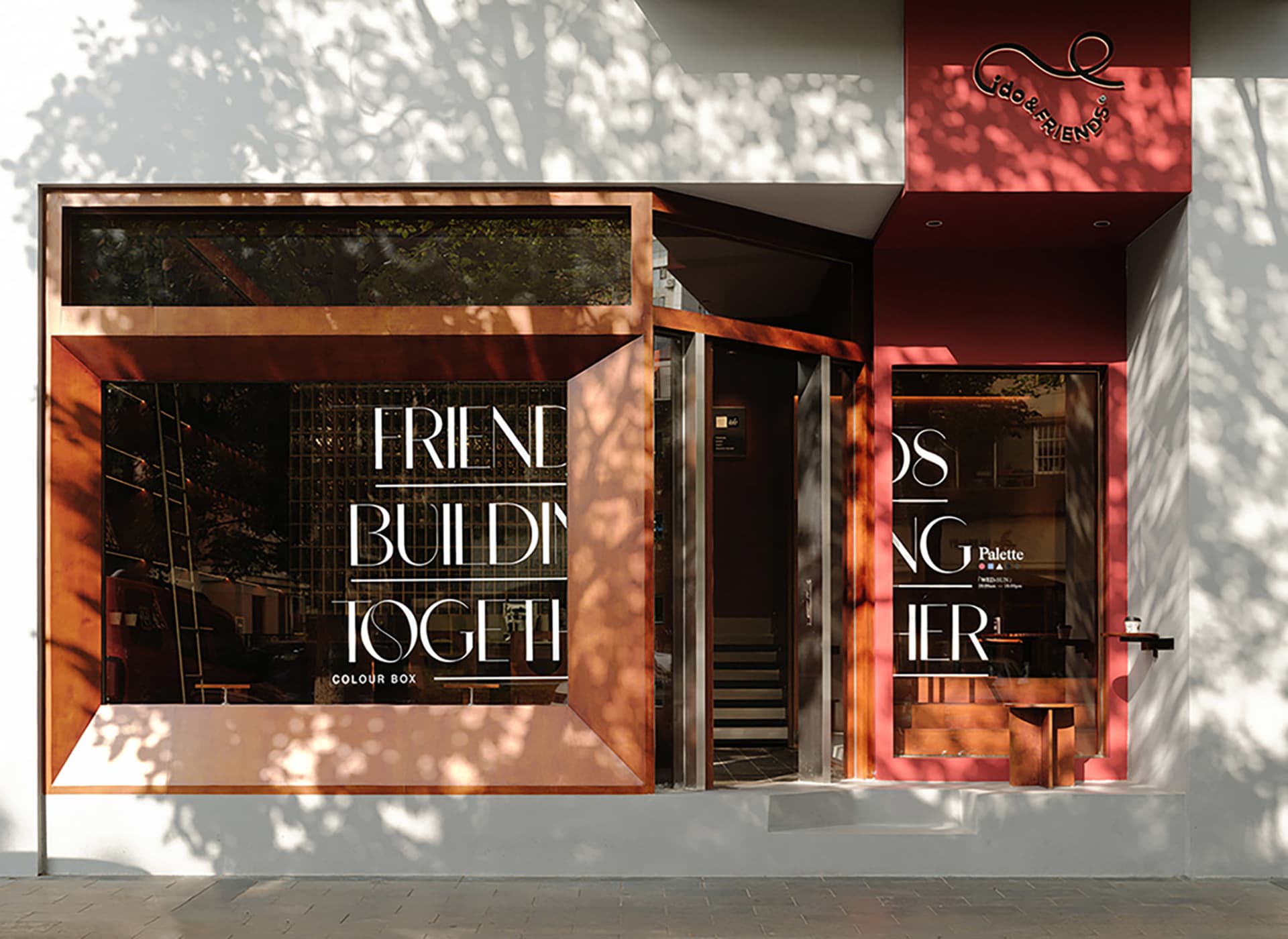 A red storefront with a large window and outdoor seating area, surrounded by signs and a welcoming atmosphere
