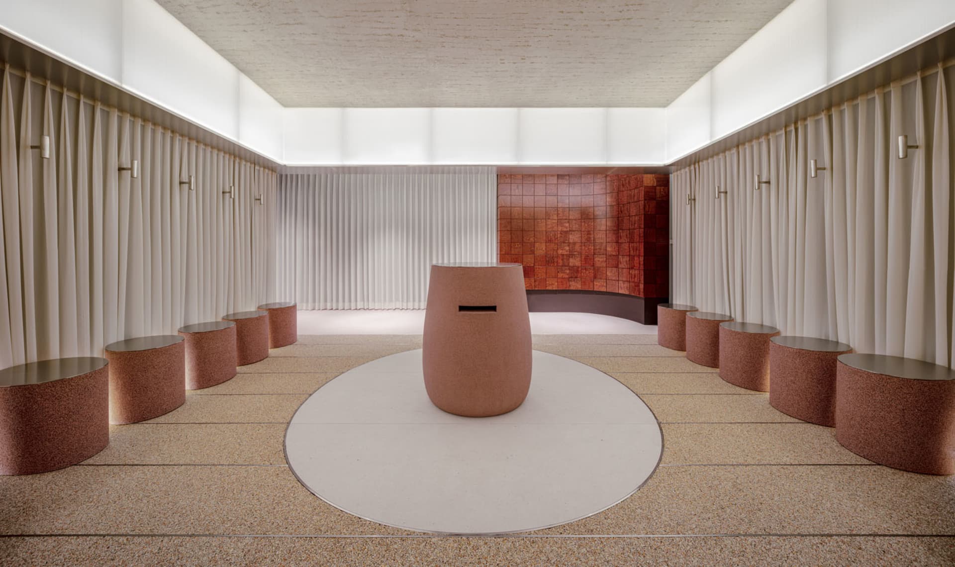 Empty modern room with a large concrete circular object in the center, high ceiling, and minimalist feel