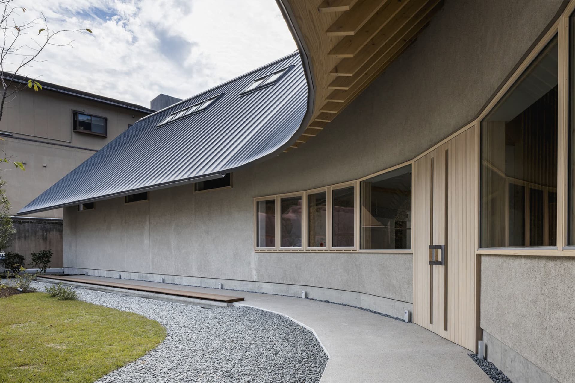 A modern house with a curved roof and large window, featuring concrete exterior walls and a well-designed atmosphere