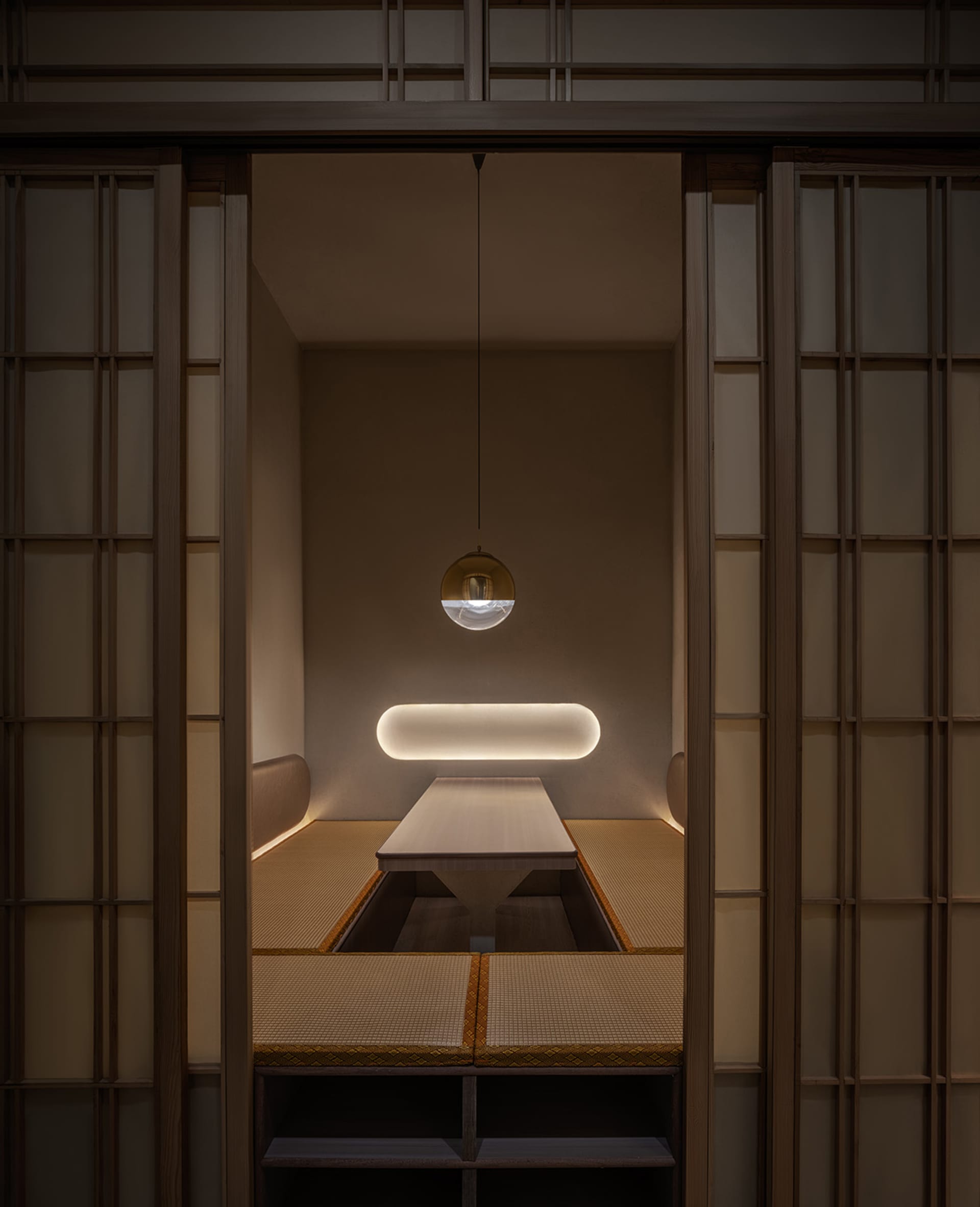 Dimly lit dining room with a symmetrical arrangement of chairs around a wooden table, creating a cozy atmosphere
