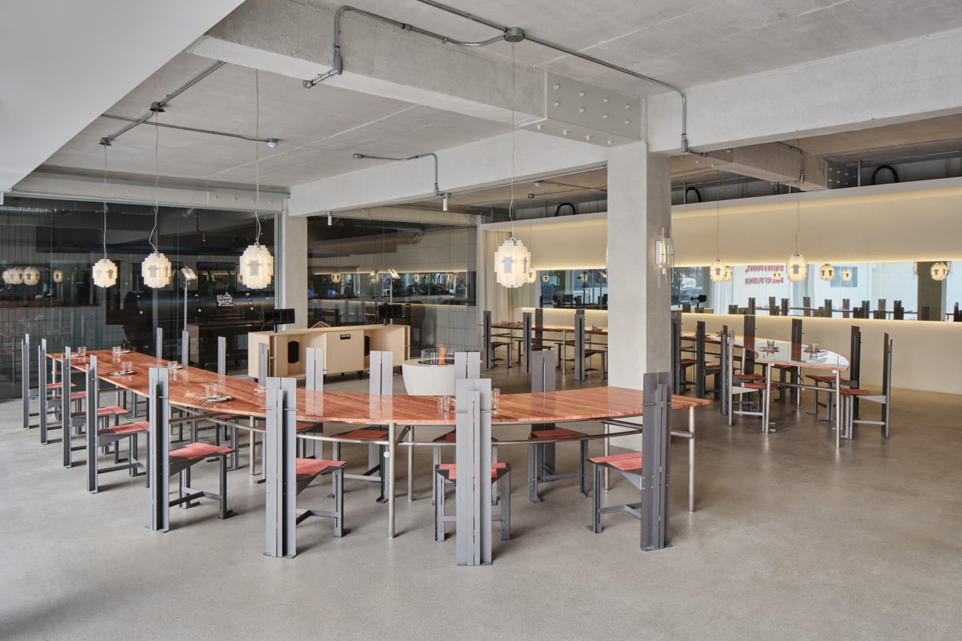 寬敞的餐廳內部，配有大型木質餐桌，周圍環繞金屬椅，營造現代極簡氛圍