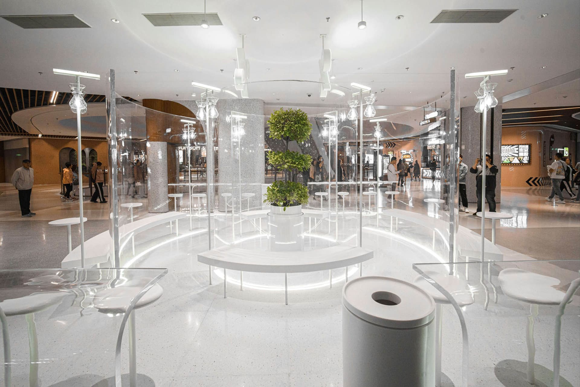 A bright and welcoming lobby with a central white tree surrounded by chairs in a circular design