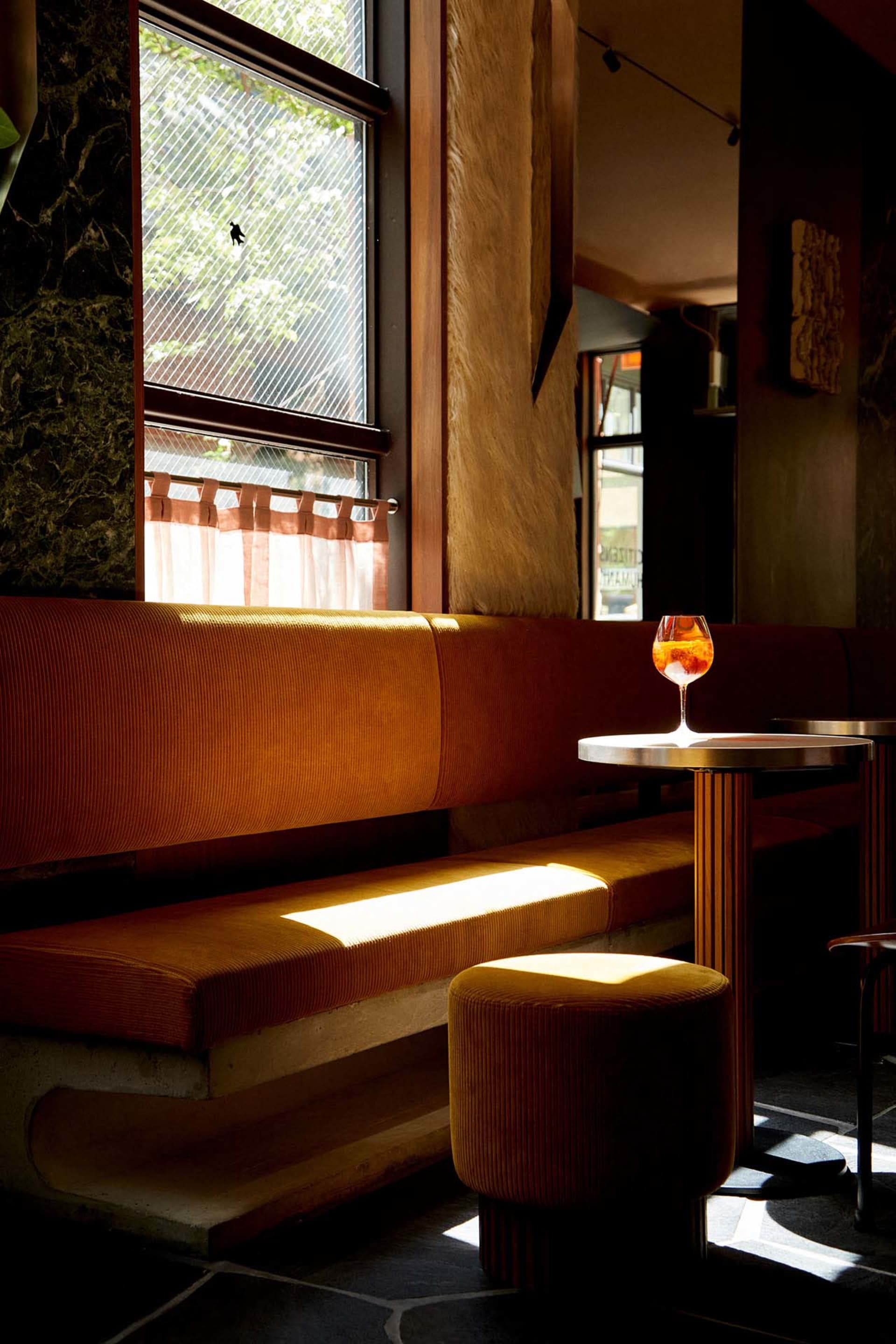 Cozy restaurant interior with wooden benches, a dining table, and a wine glass, inviting atmosphere