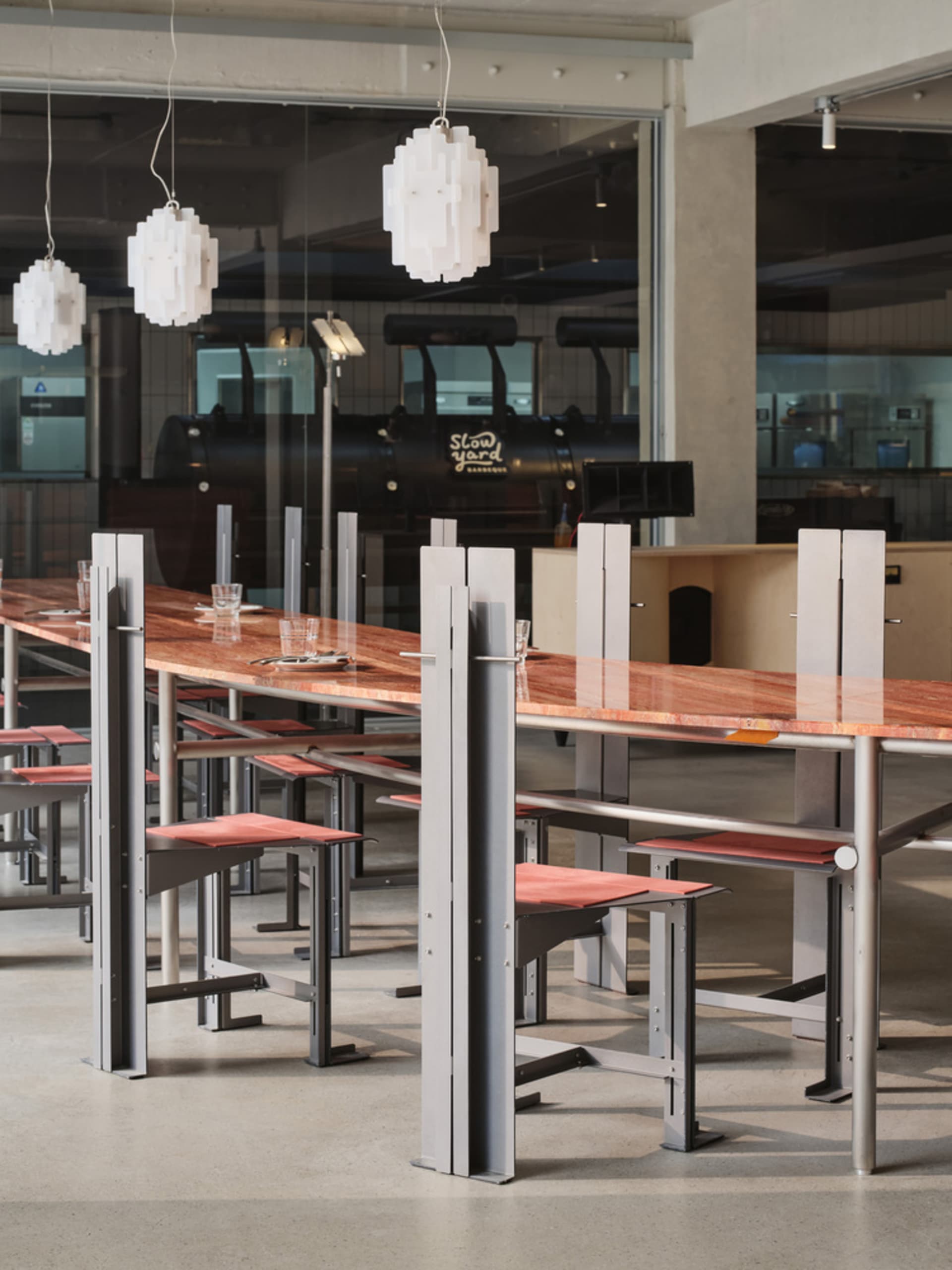 Industrial restaurant with a long wooden table and metal chairs, well-lit with natural and artificial light