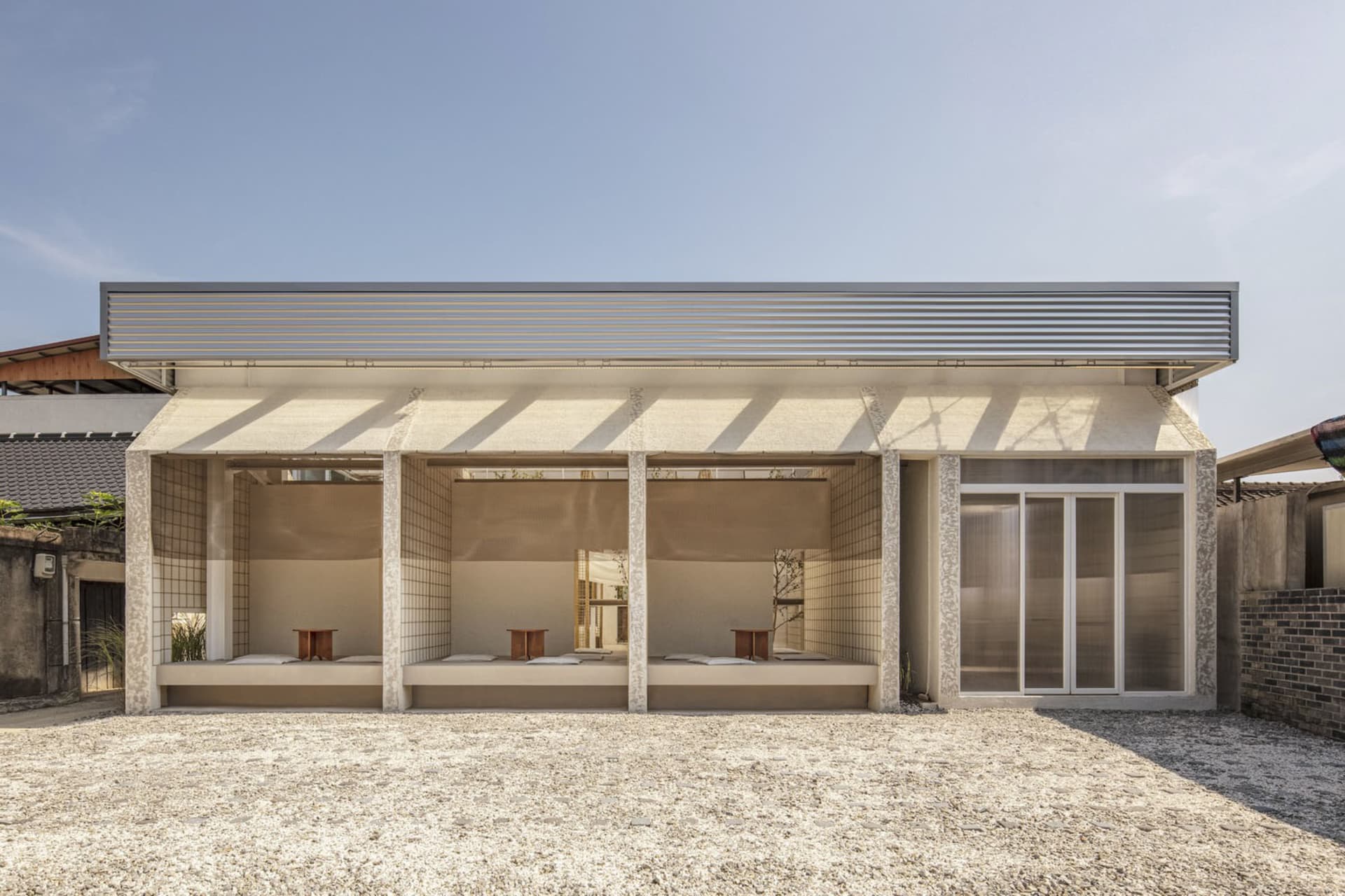 A modern outdoor dining space with a concrete patio, a dining table, and chairs, filled with natural light