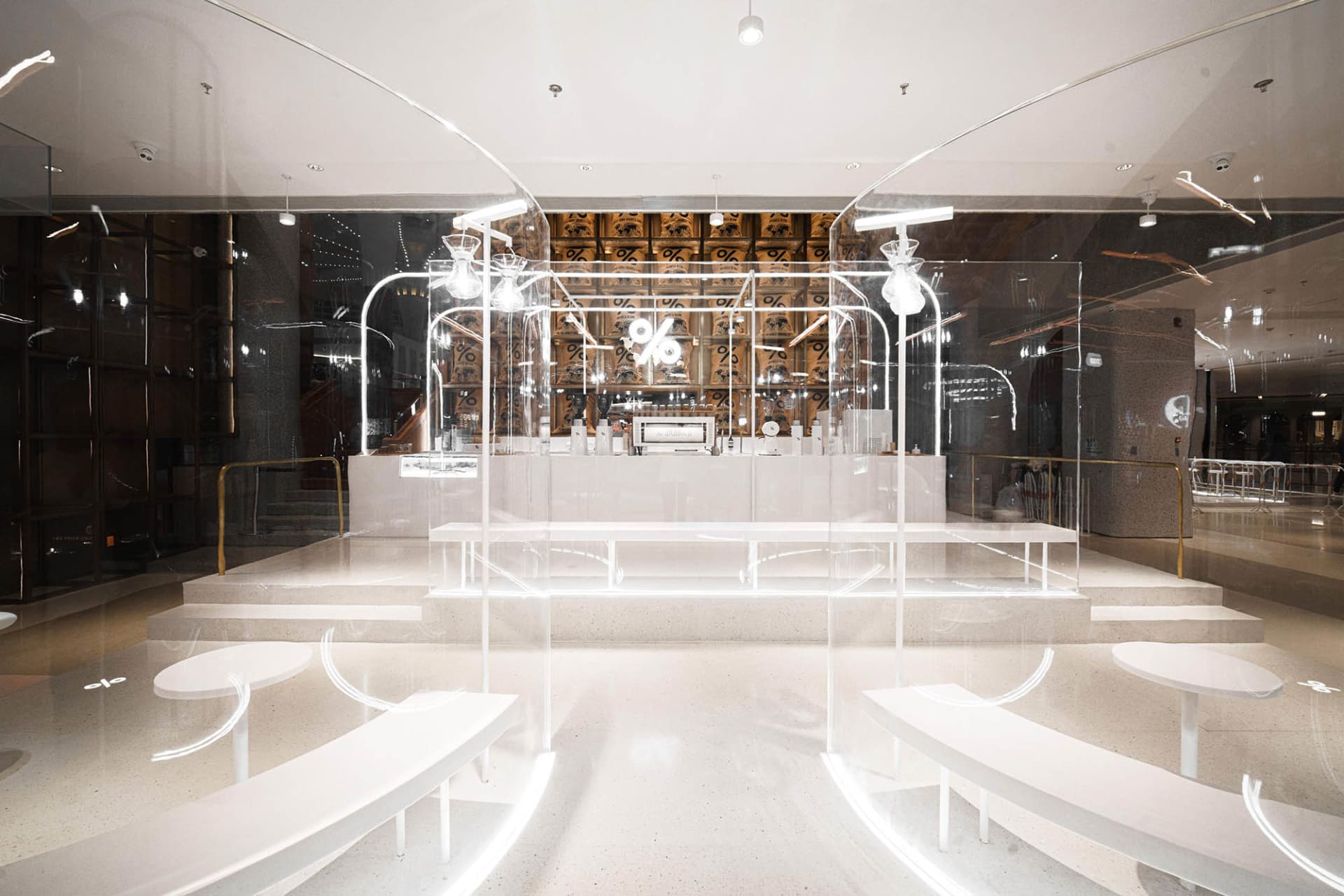 A modern cafe with white walls and floors, featuring benches and chairs for seating, creating an inviting and comfortable atmosphere
