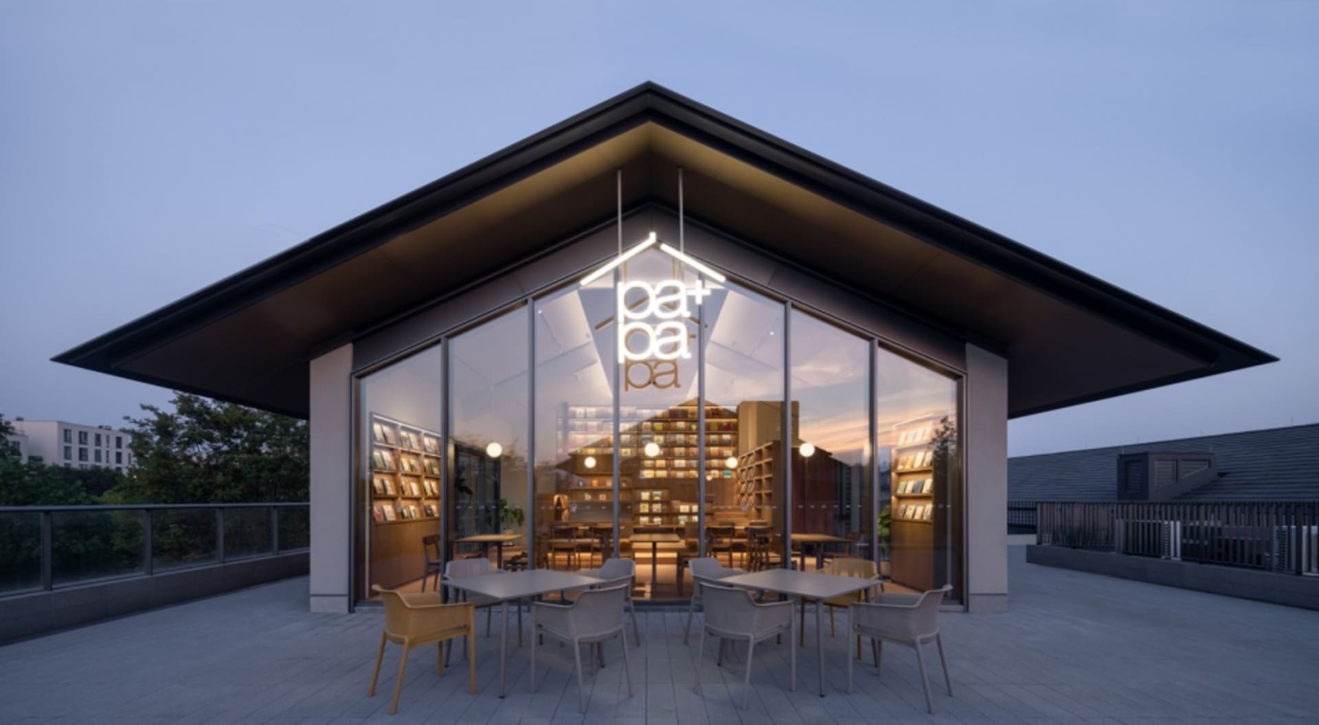 A modern restaurant interior with a large dining area, tables, chairs, books, and a cozy atmosphere