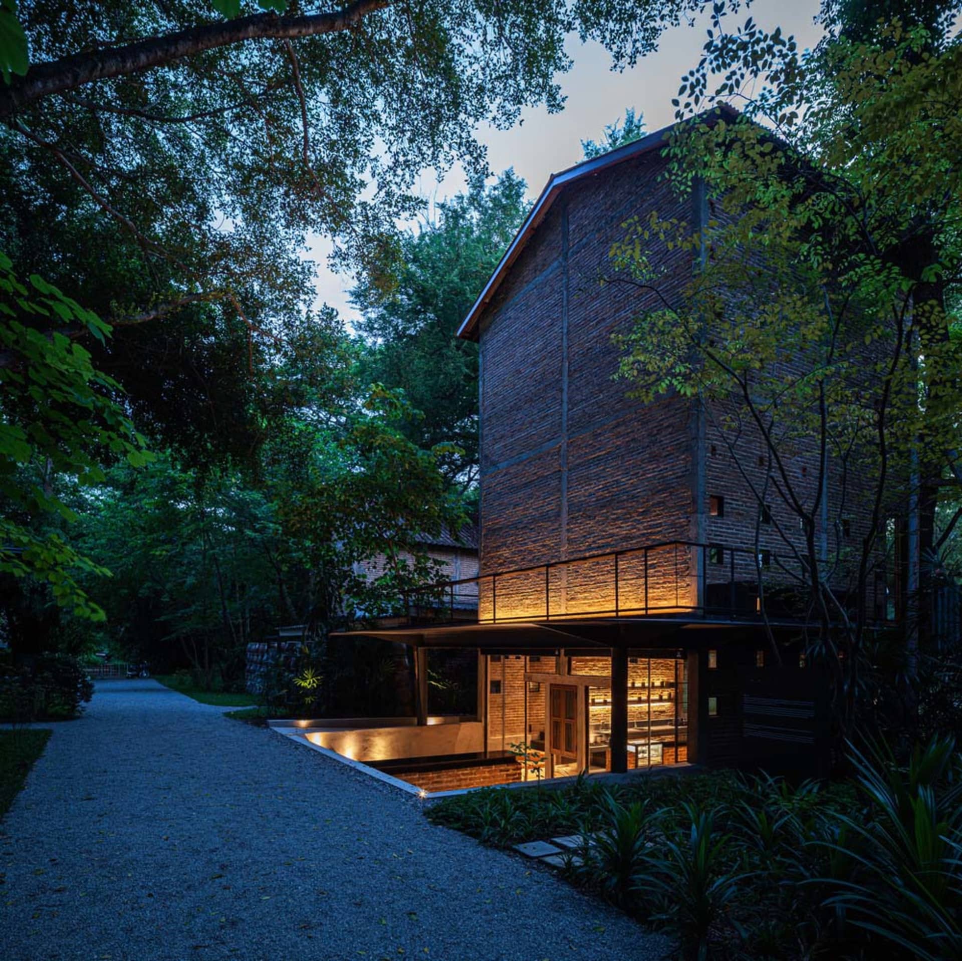 A brick house with a wooden structure and stone exterior, well-lit by artificial lights at night, with several windows for natural light