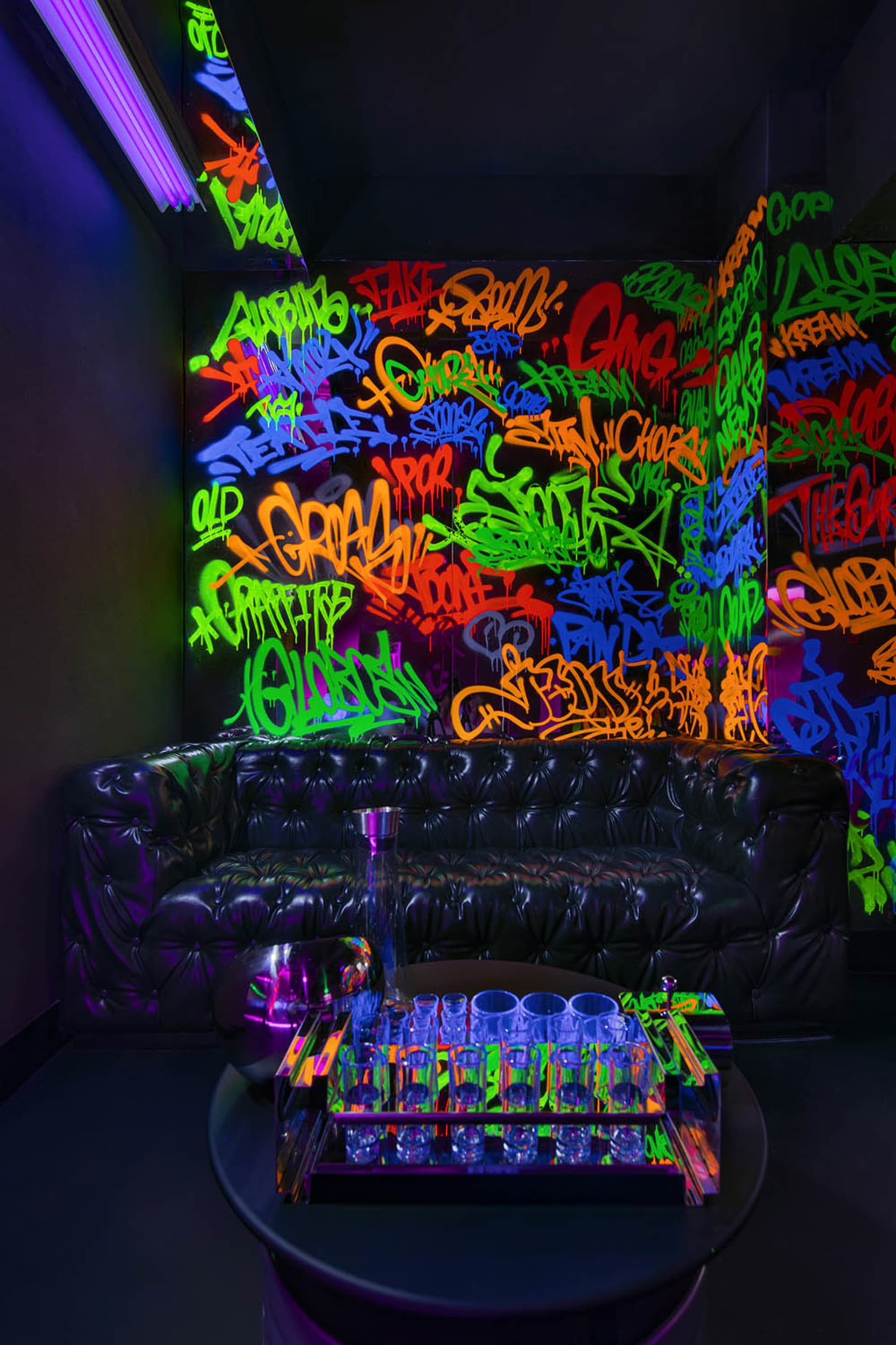 A modern living room with graffiti artwork, two couches, a chair, and a table with a vase and cup, creating a unique urban atmosphere