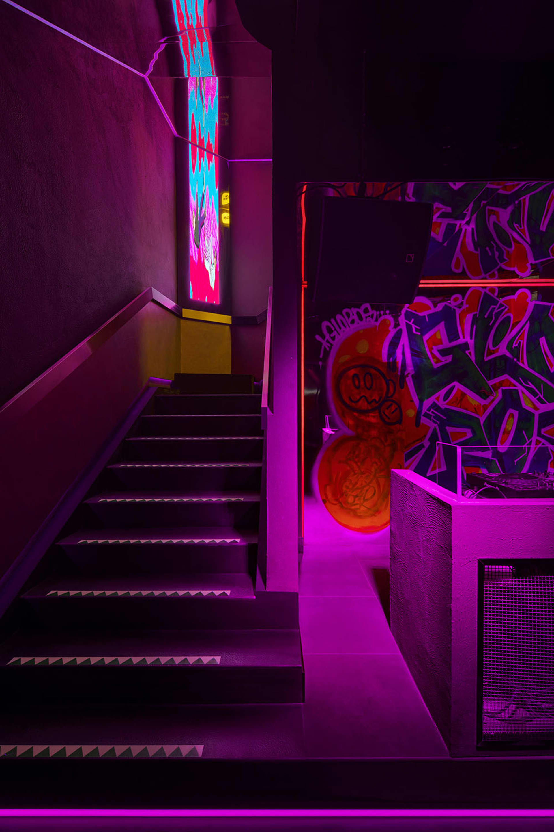 A purple-lit stairwell with graffiti on the walls, creating a modern and artistic atmosphere