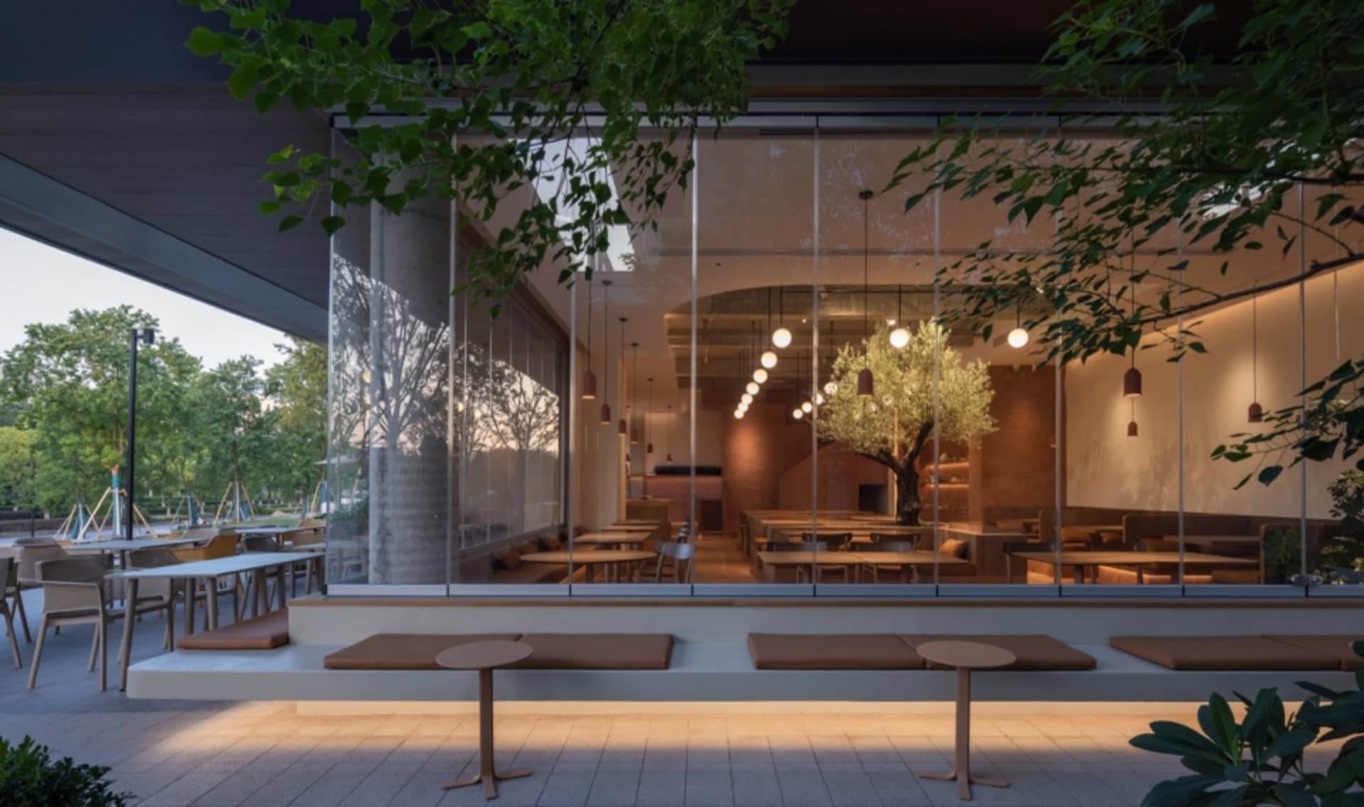 明亮溫馨的餐廳內部，大片窗戶、餐桌椅，配有遮陽傘增添舒適陰涼