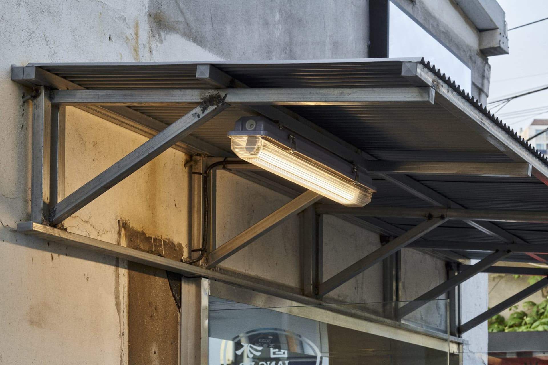 A building's underside with a metal roof and a car parked underneath, showcasing its design elements and structure